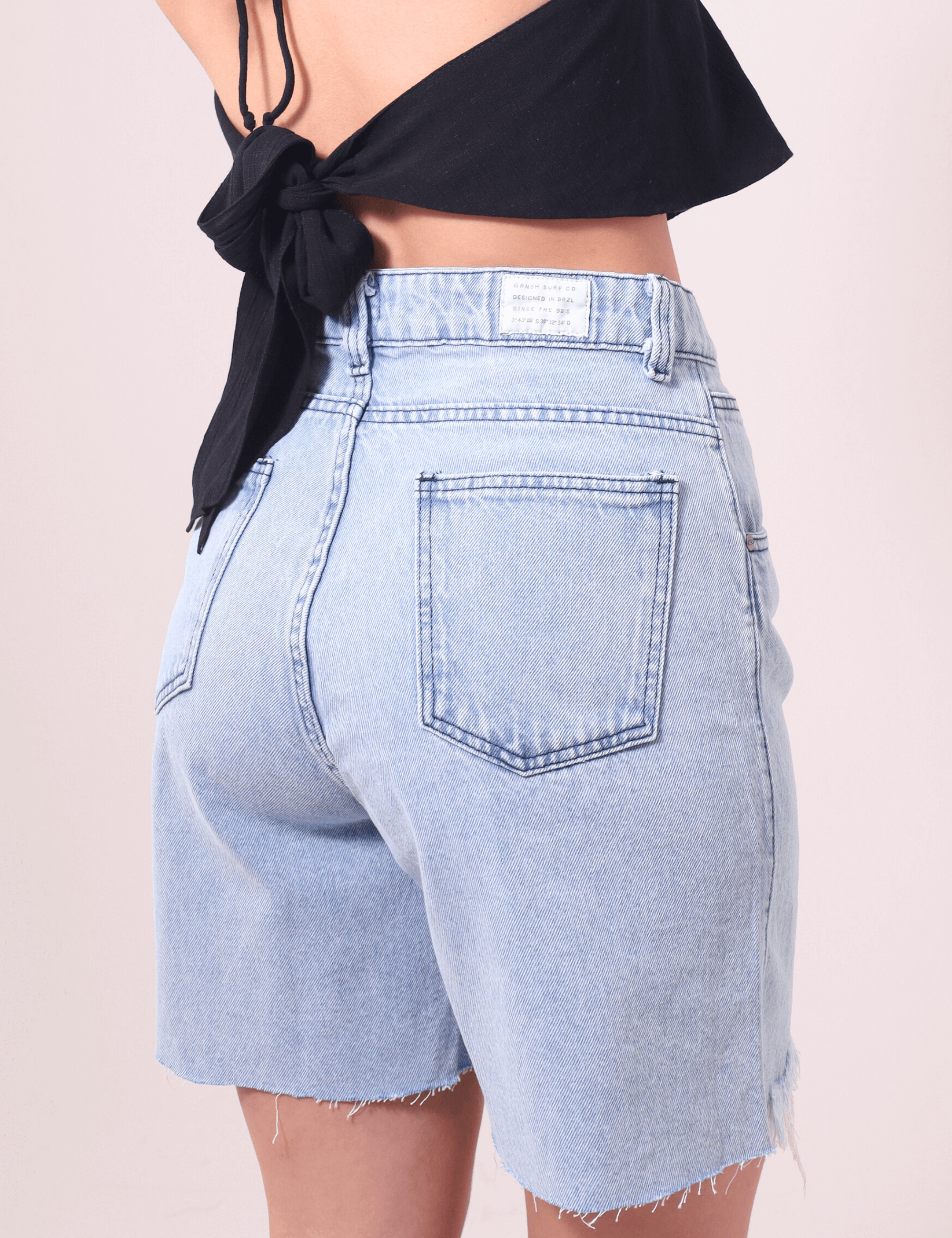 Bermuda Jeans Glicia da Greenish com cintura alta e caimento solto, lavagem azul vintage e acabamento desfiado. Moda verão atemporal.