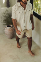 Homem vestindo Bermuda Sarja Hamie - Caqui da Greenish, estilo casual minimalista, com visual urbano e essência litorânea.