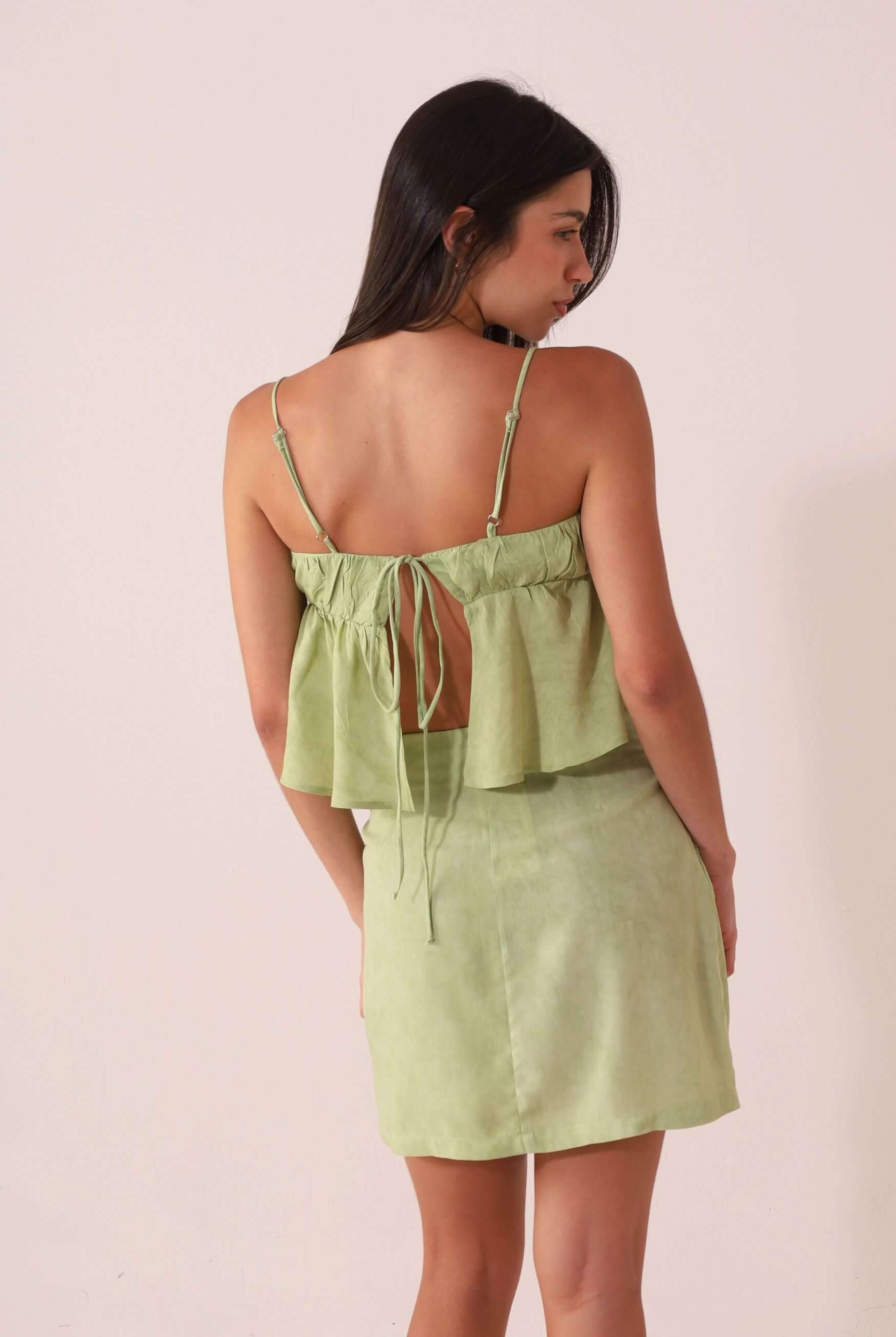 Mulher de costas vestindo a BLUSA THÁ - VERDE da Greenish, com alças finas e design romântico em viscose texturizada.