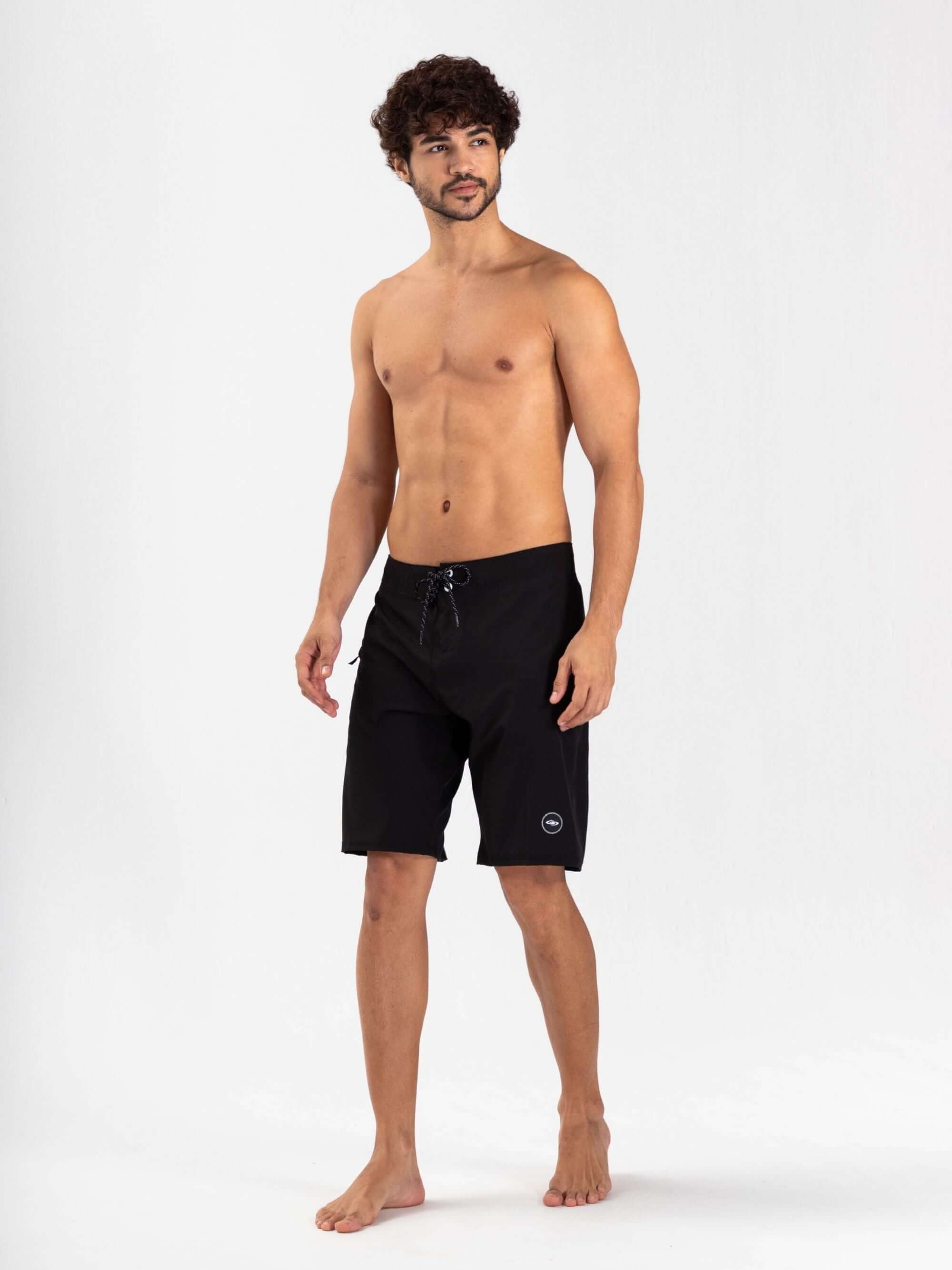 Modelo masculino usando boardshort Total Stretch Preto da Greenish, ideal para surf e aventuras aquáticas.