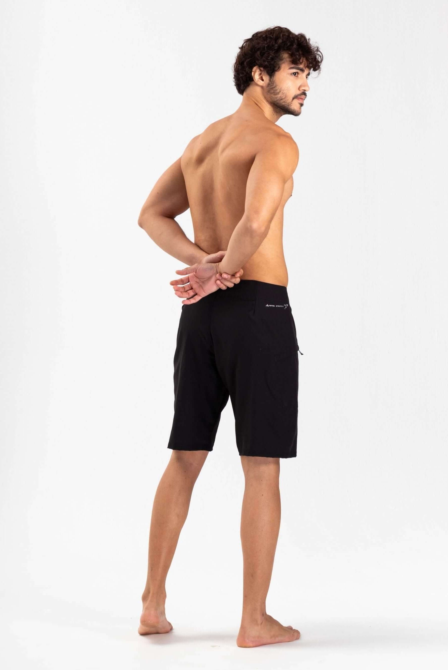 Modelo usando boardshort Total Stretch Preto da marca Greenish, mostrando a parte de trás da peça, ideal para alta performance no mar.