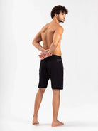 Modelo usando boardshort Total Stretch Preto da marca Greenish, mostrando a parte de trás da peça, ideal para alta performance no mar.