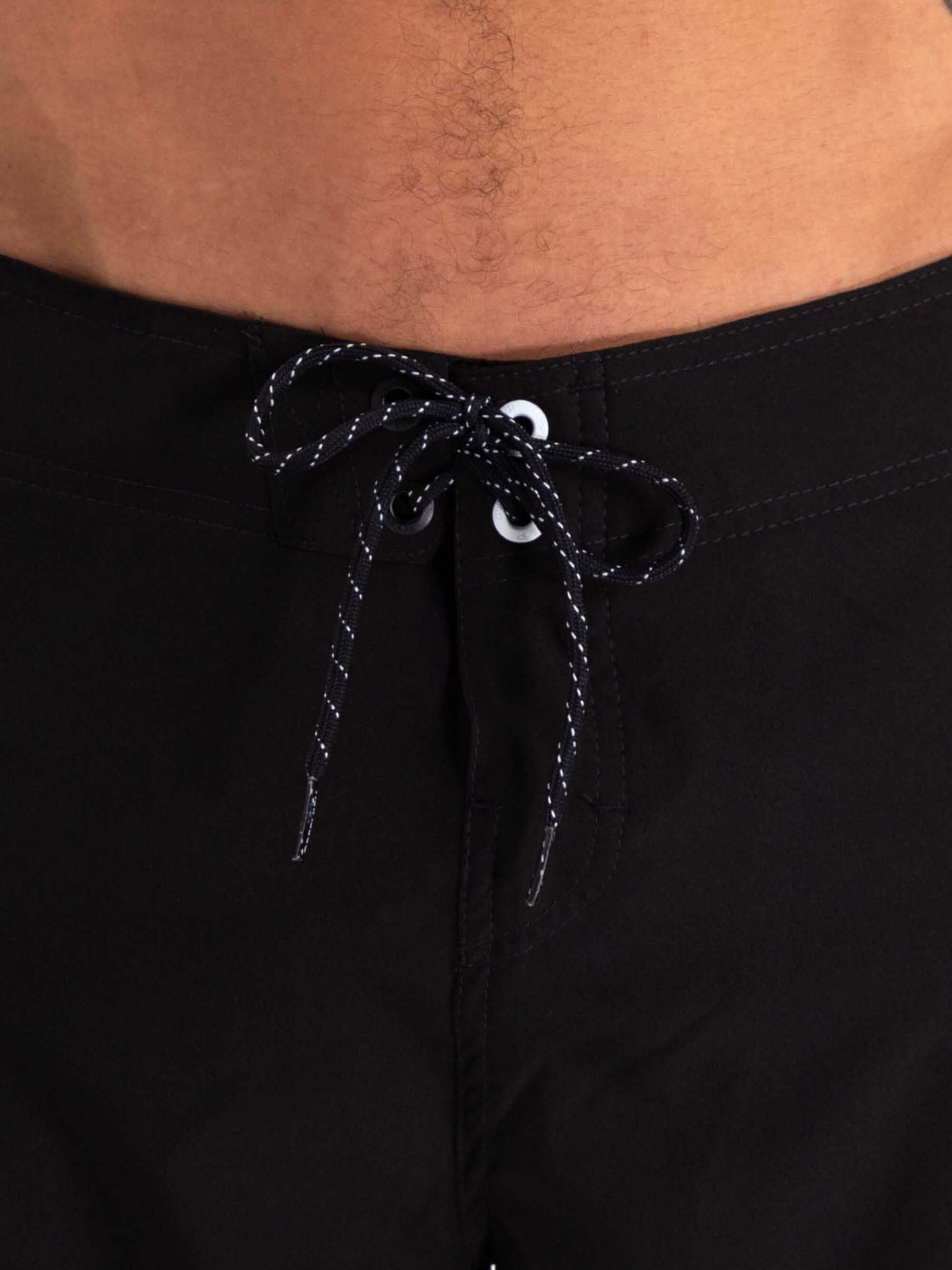 Close-up of Greenish Ultralight Basic boardshort in black, showcasing waist drawstring and stretch fabric for comfort.