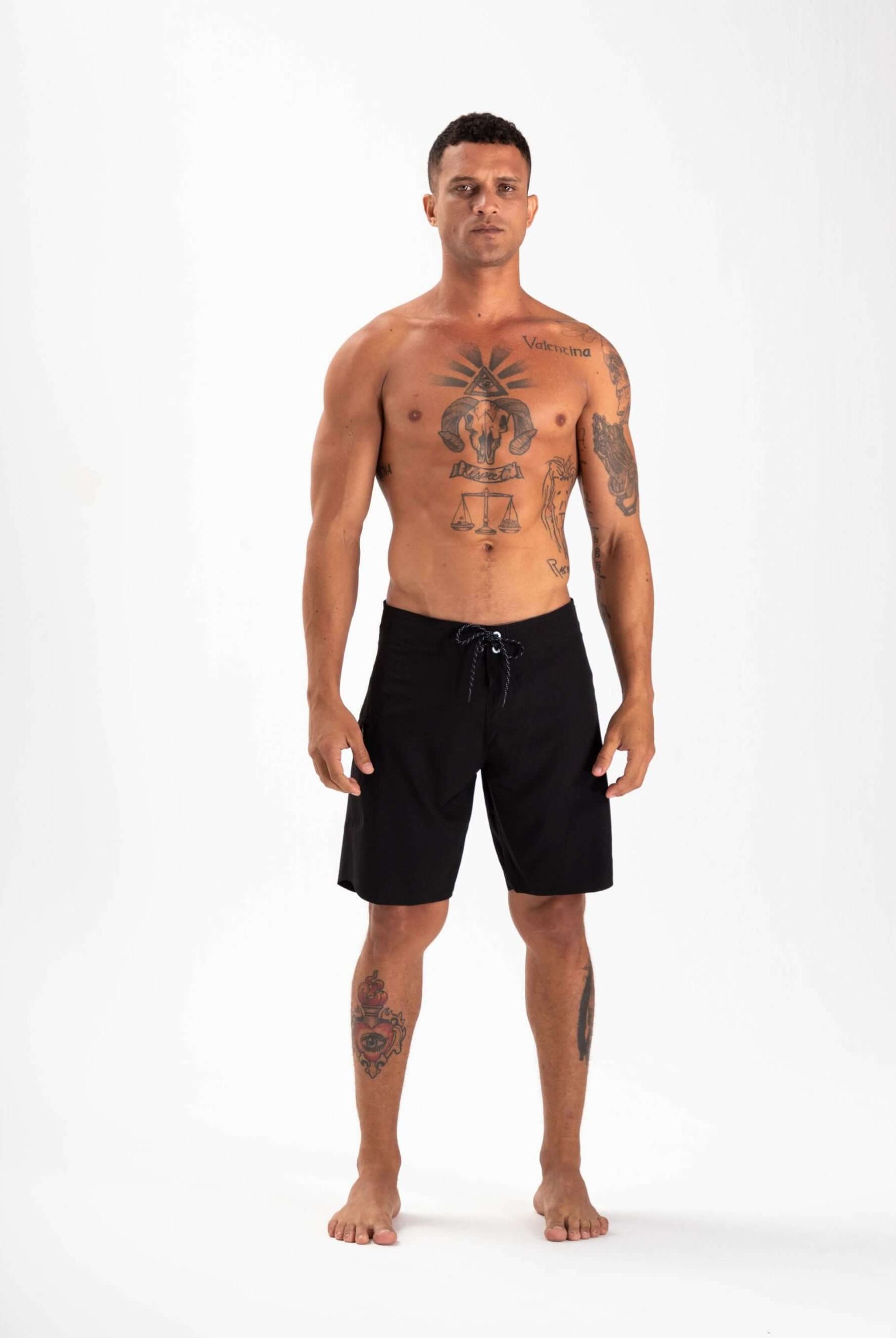 Homem posando com boardshort Ultralight Basic Preto da Greenish, ideal para desempenho em esportes aquáticos.