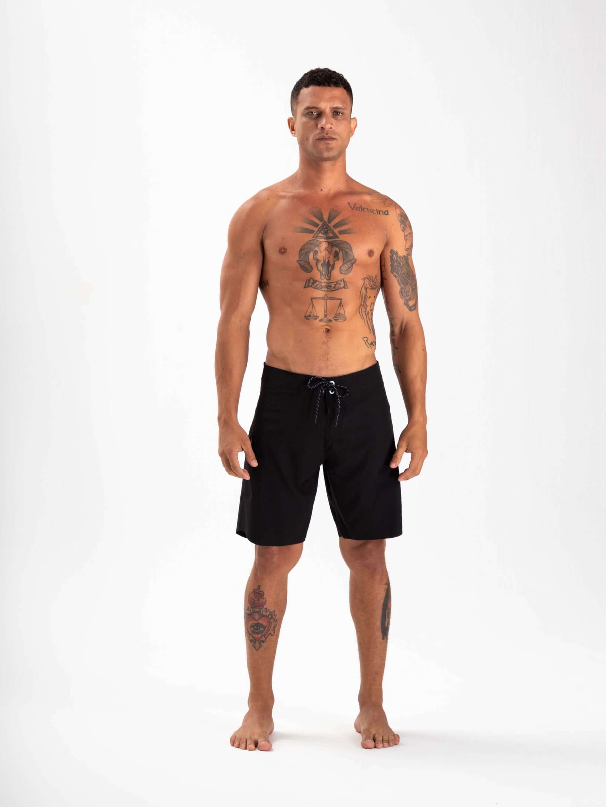 Homem posando com boardshort Ultralight Basic Preto da Greenish, ideal para desempenho em esportes aquáticos.