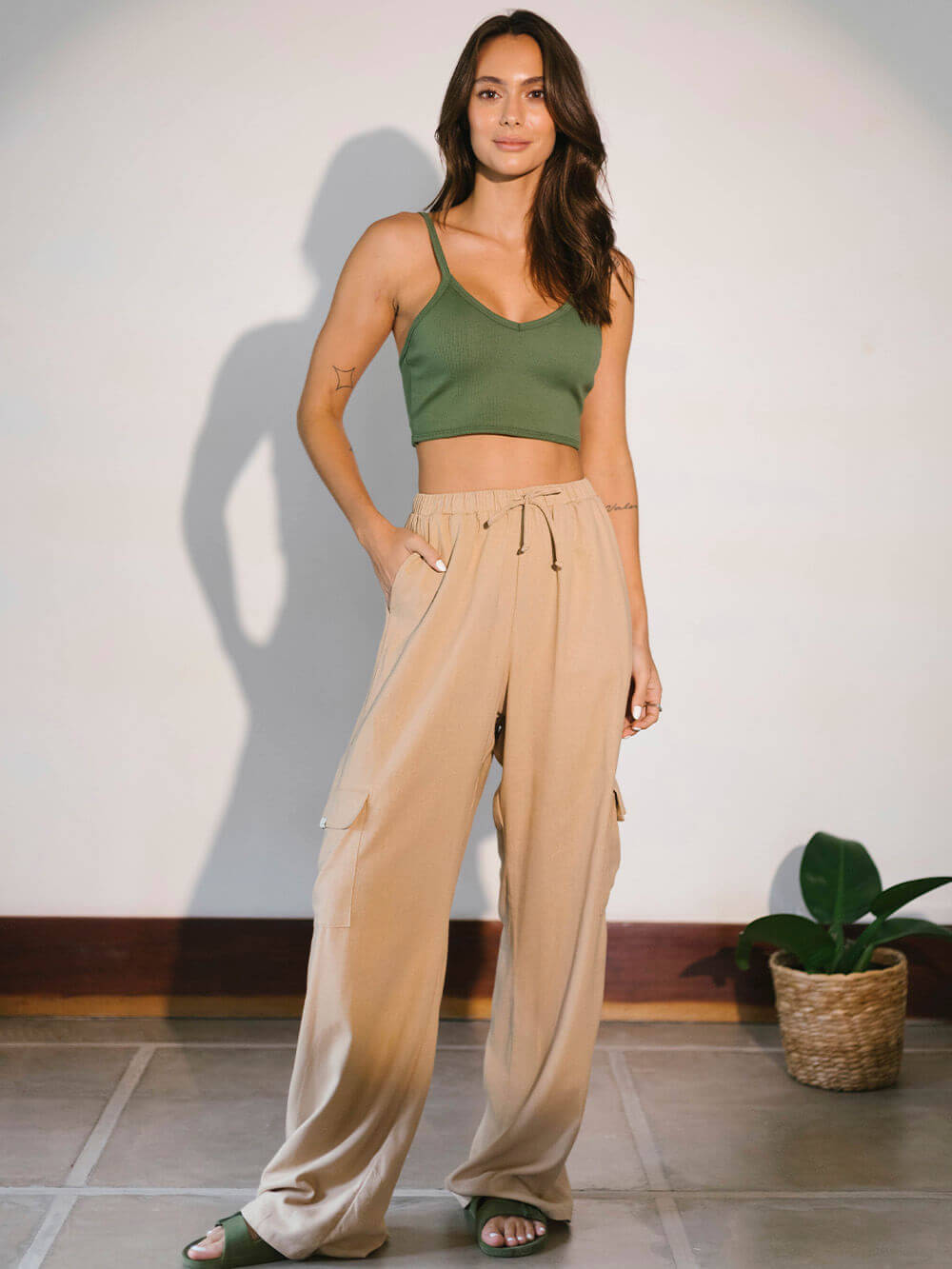 Modelo usando top verde e calças largas em ambiente iluminado, representando conforto e estilo da marca Greenish.