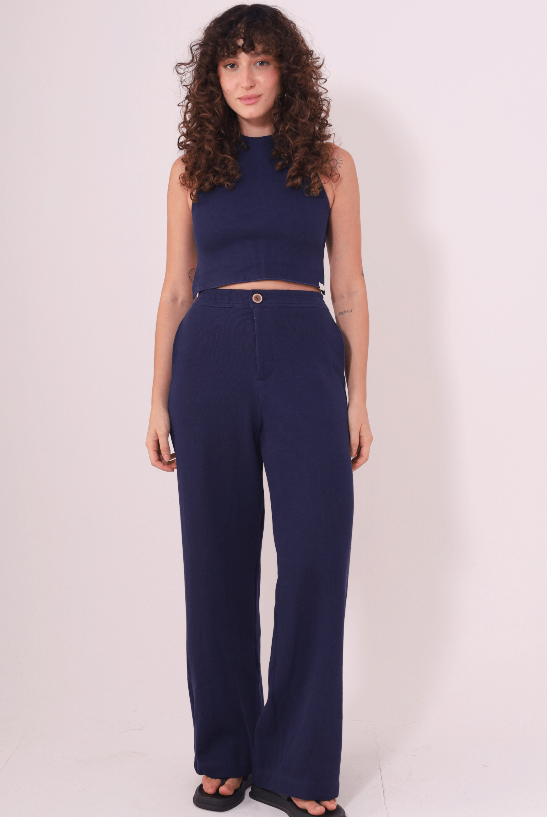 Mulher vestindo Calça Lina azul marinho da Greenish, feita em Tricot Bloom 100% algodão, com caimento reto e cintura média.