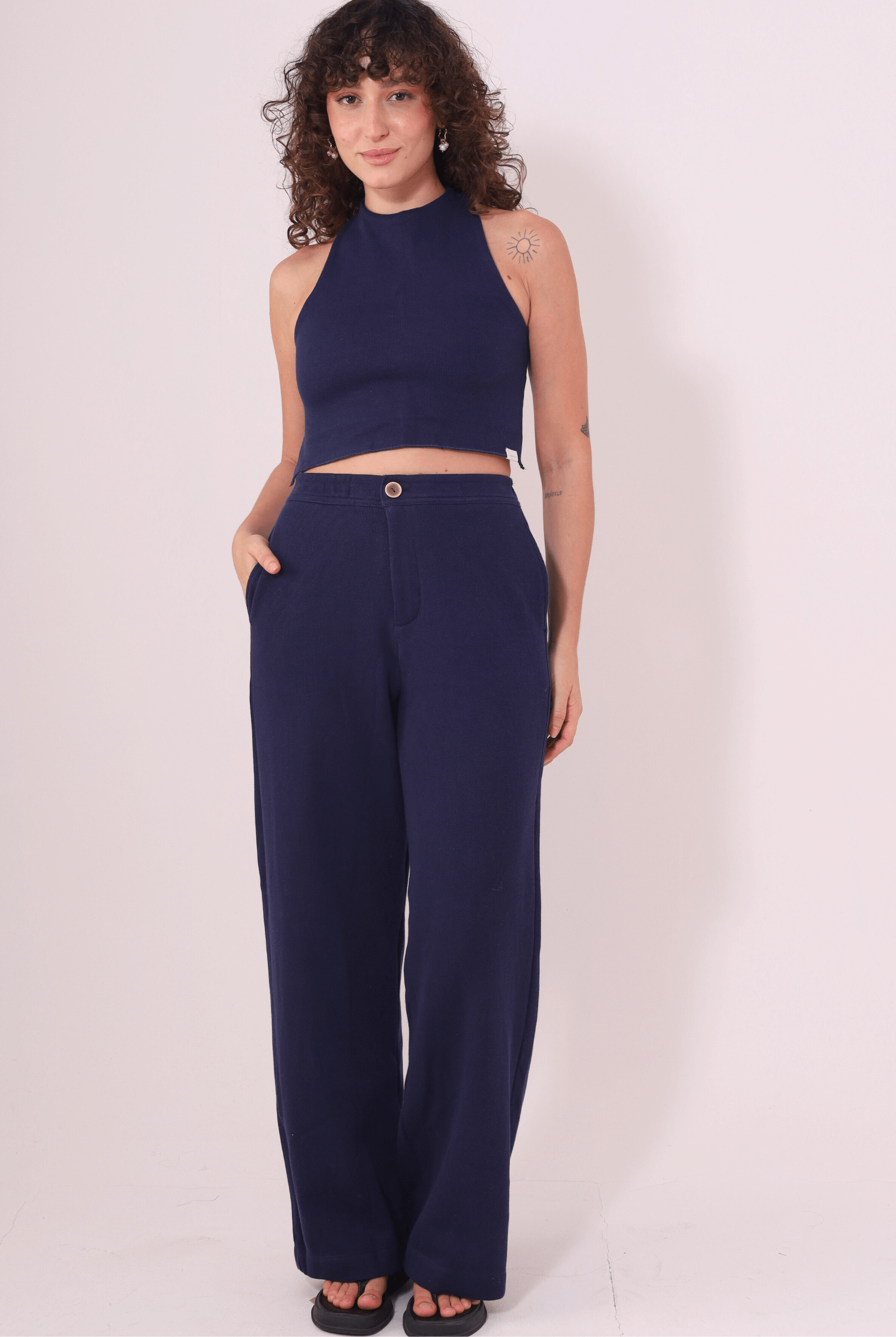 Modelo vestindo Calça Lina Azul Marinho da Greenish em malha 100% algodão, com caimento reto e bolso lateral. Ideal para conforto e estilo.