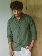 Homem usando camisa longa de linho verde da Greenish, com botões de coco, em cenário casual.