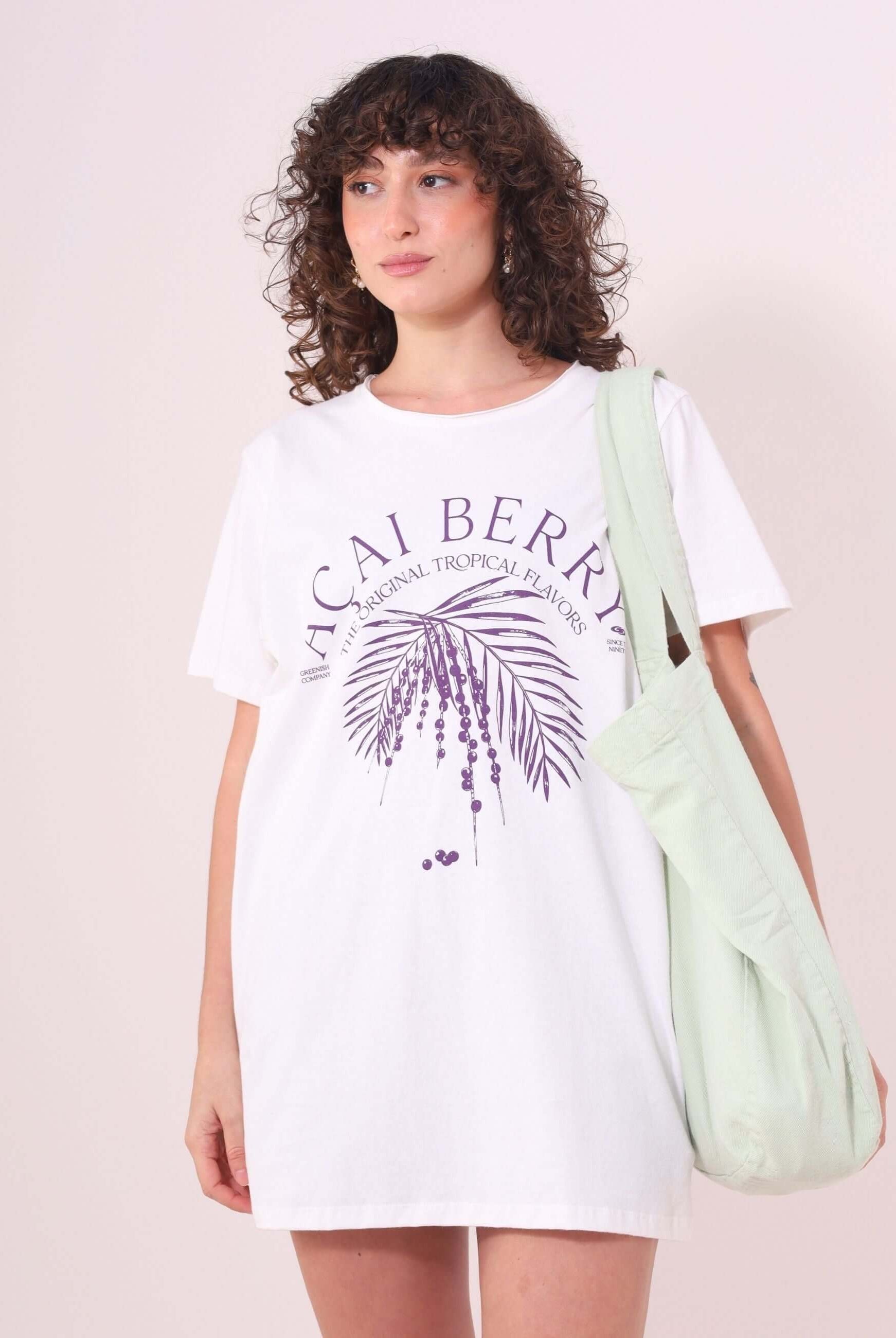 Mulher usando Camiseta Açai Berry em off white da marca Greenish, feita de algodão 100%, com estampa tropical roxa e modelagem ampla.
