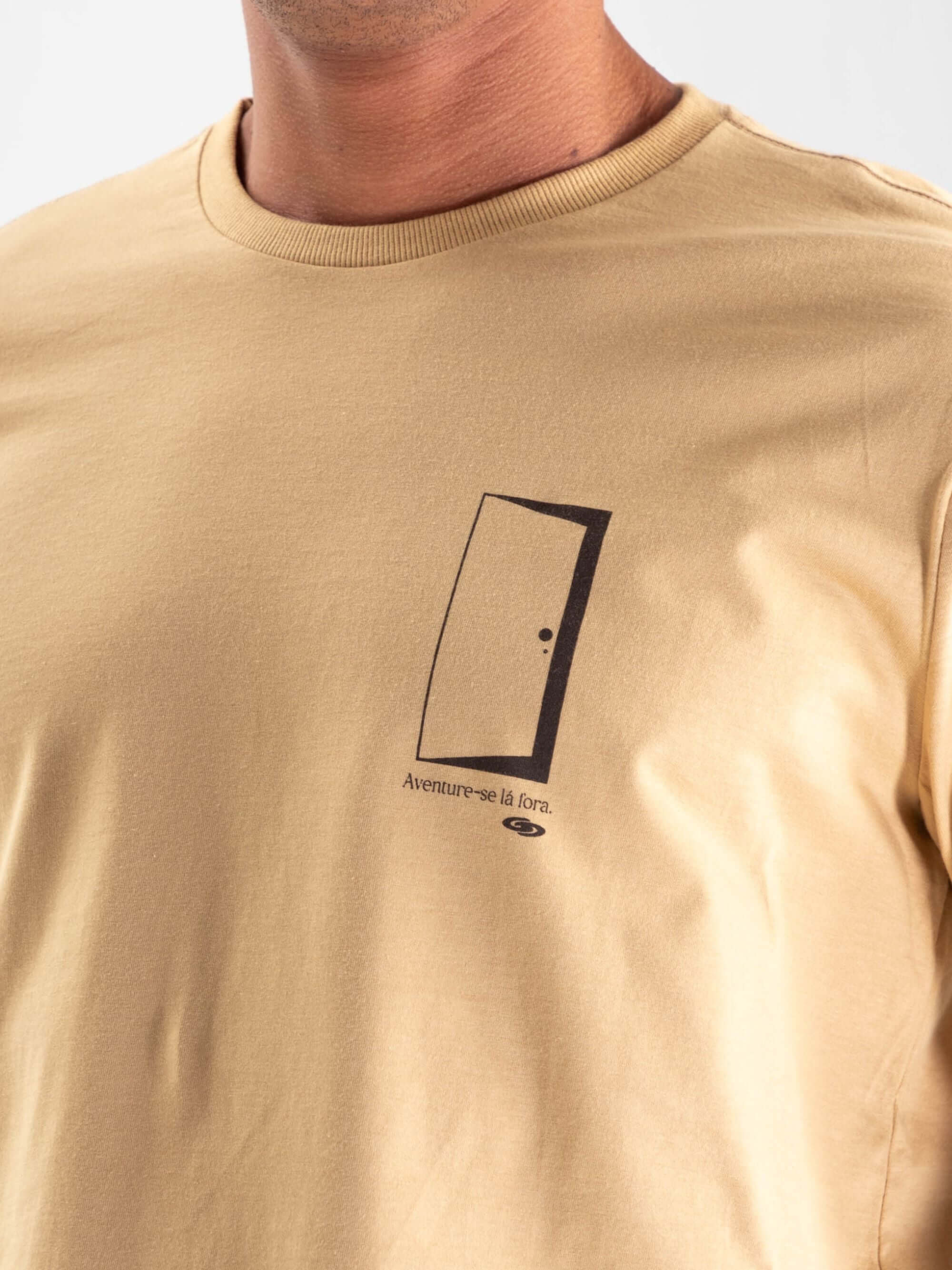 Camiseta caqui 'Aventure-se Lá Fora' da Greenish, destacando estampa de porta como símbolo de exploração.