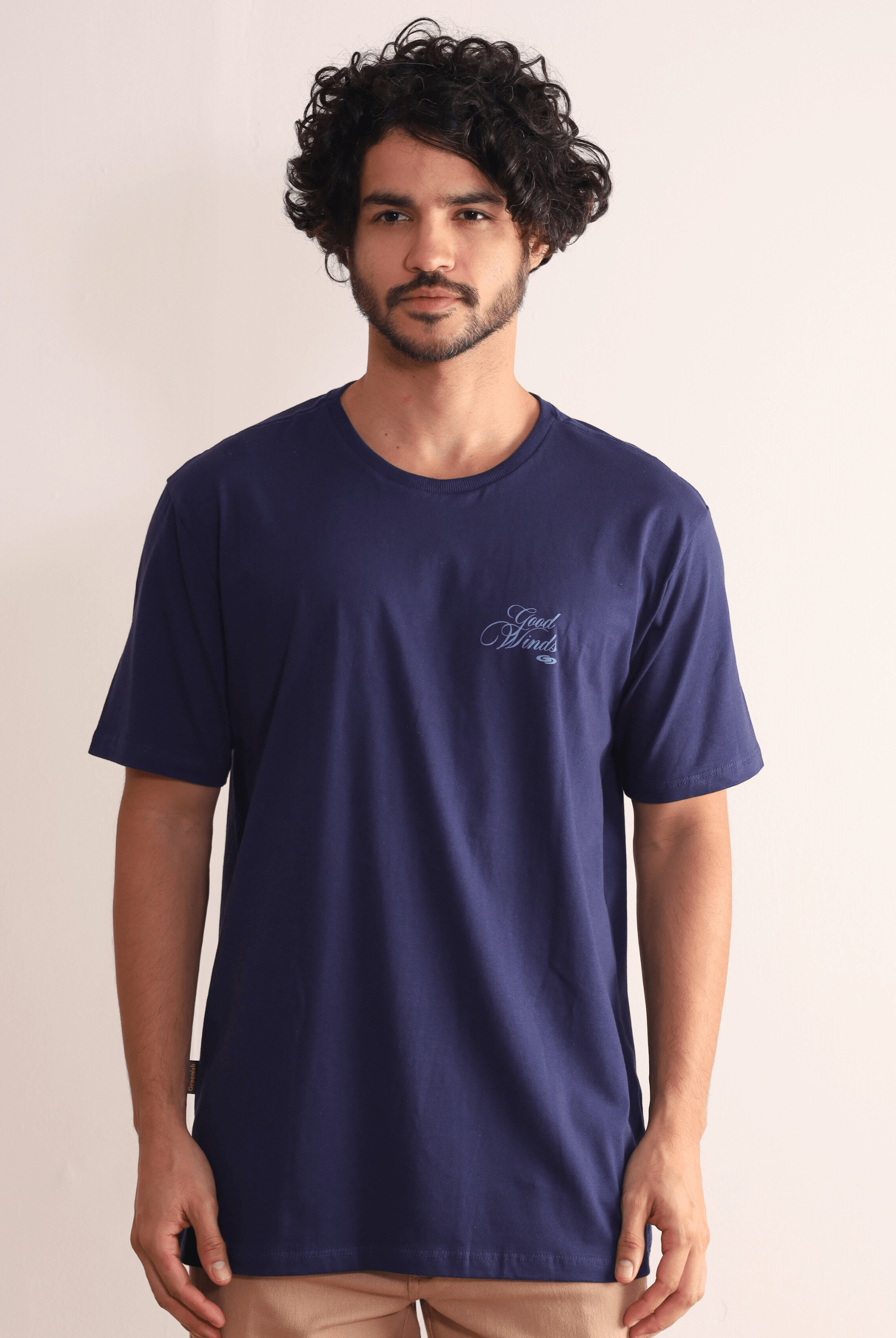 Modelo vestindo Camiseta Greenish Kites & Good Winds azul marinho com bordado frontal, macia e durável em algodão de alta qualidade.