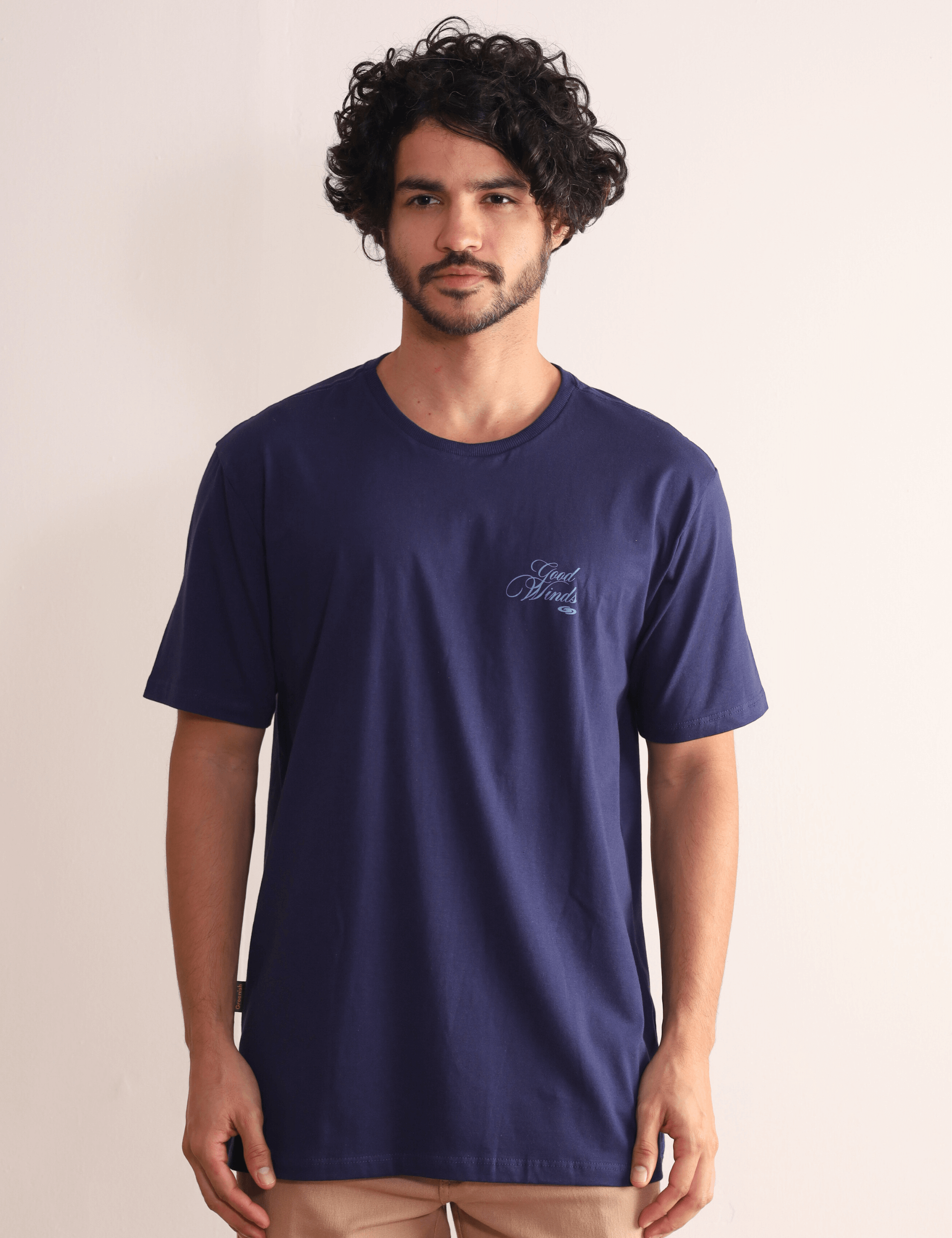 Modelo vestindo Camiseta Greenish Kites & Good Winds azul marinho com bordado frontal, macia e durável em algodão de alta qualidade.