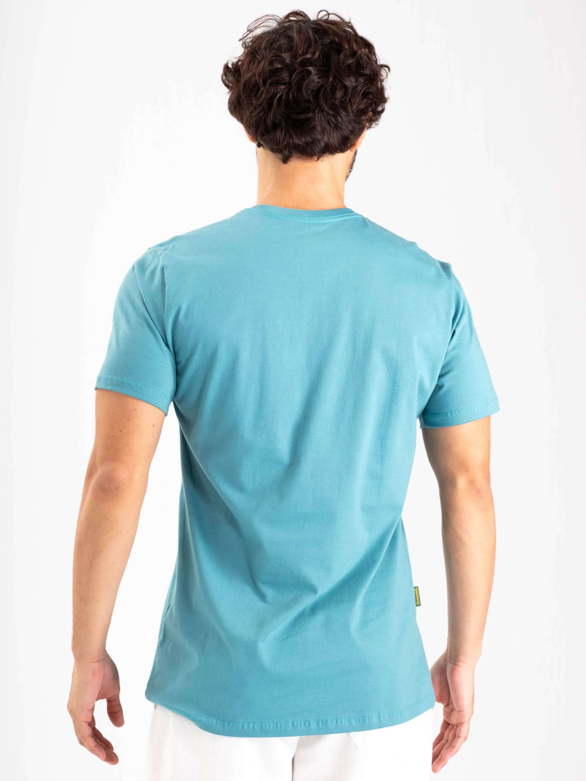 Modelo usando camiseta Bons Ventos azul médio da Greenish, vista traseira, ideal para esportes aquáticos e combinações casuais.