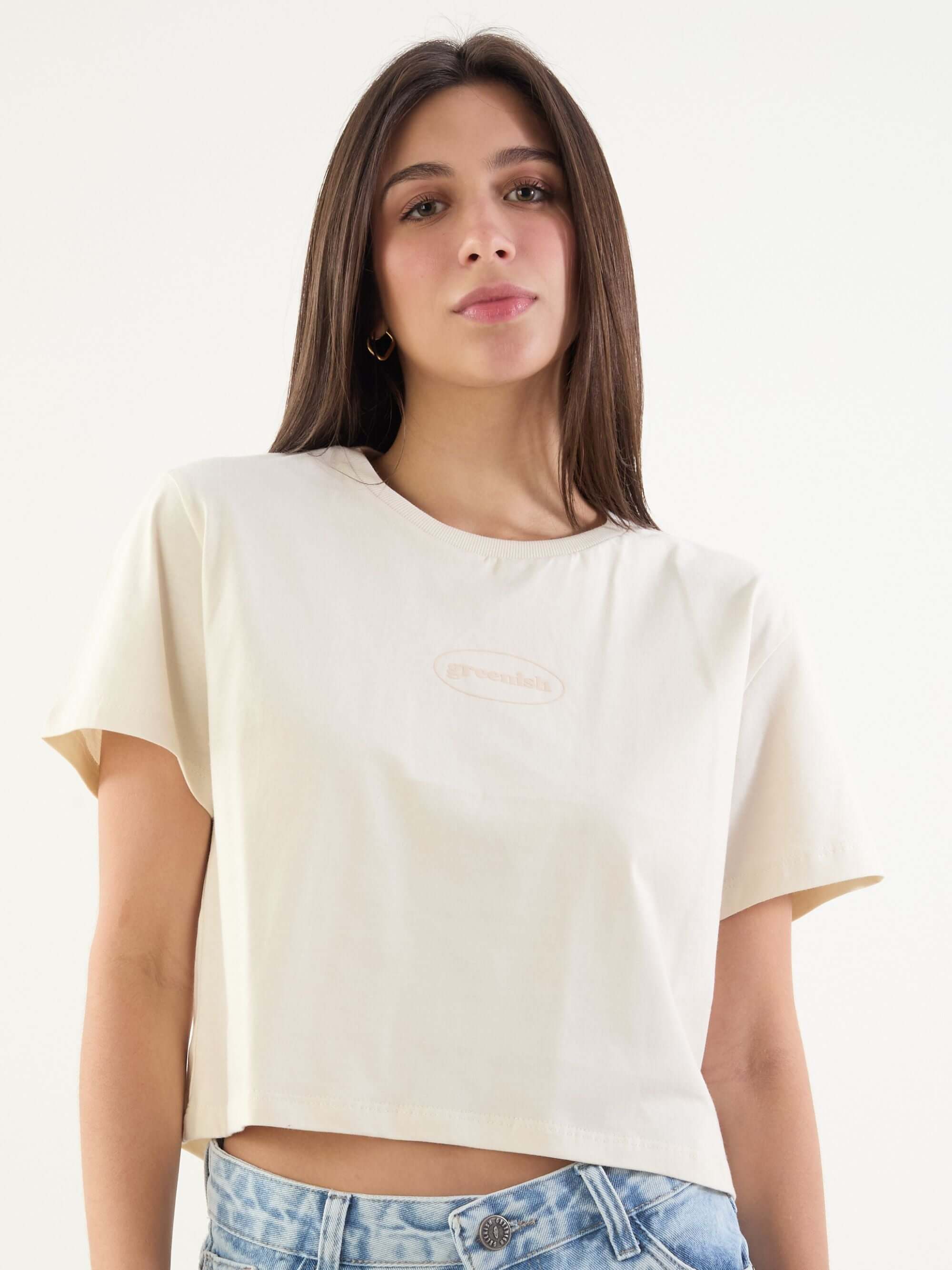 Camiseta cropped bege da marca Greenish, com manga curta e estilo moderno, ideal para lookscasuais.