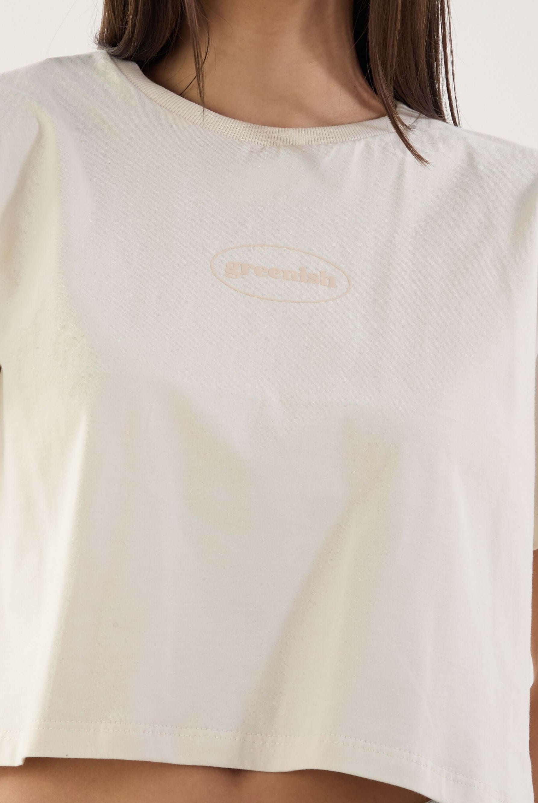 Camiseta cropped beige da marca Greenish, com logo em destaque, estilo moderno e confortável.