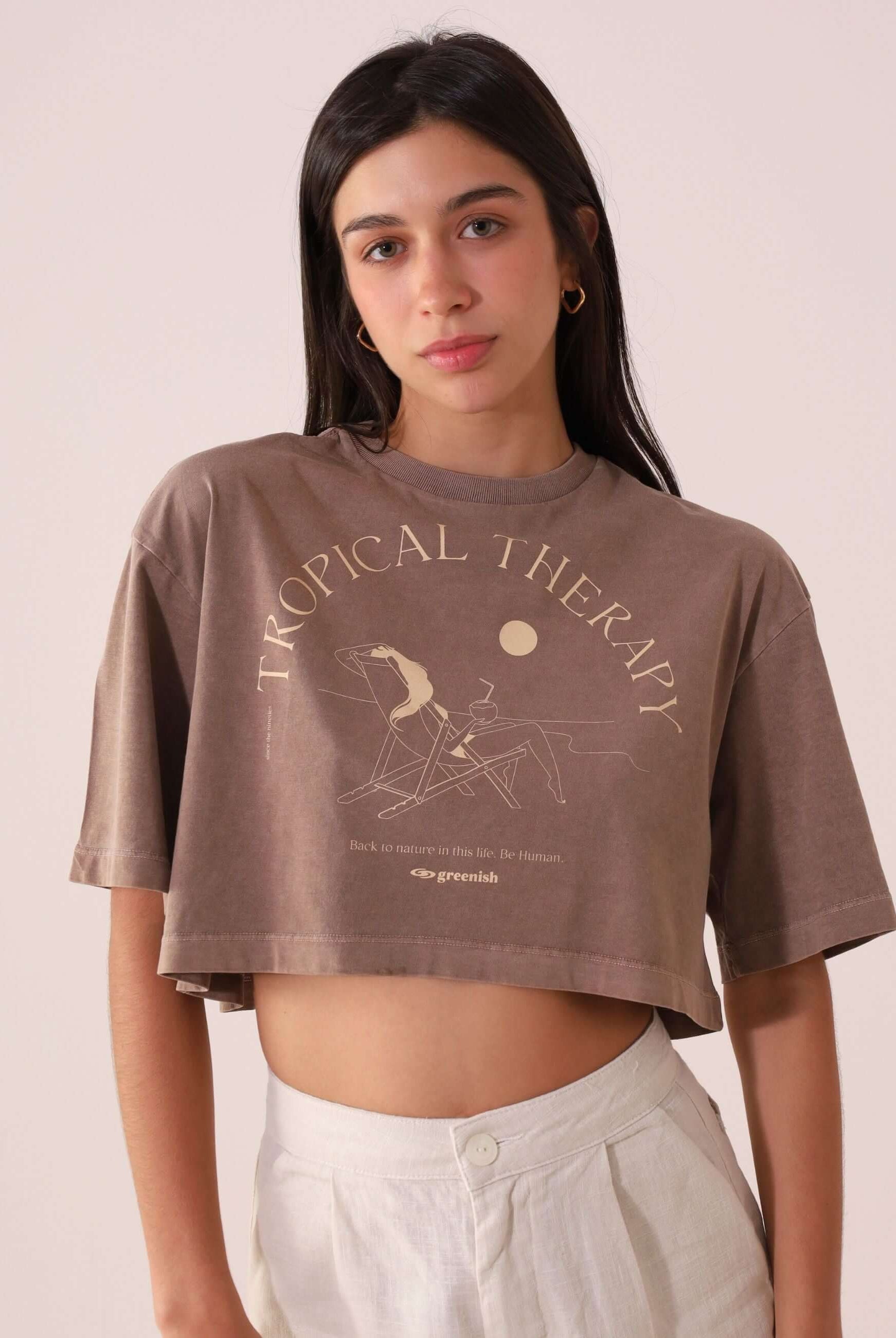 Mulher vestindo camiseta Greenish CROPPED STONE RELAXING VIEW - MARRON, estilo oversized, com estampa Tropical Therapy vintage.
