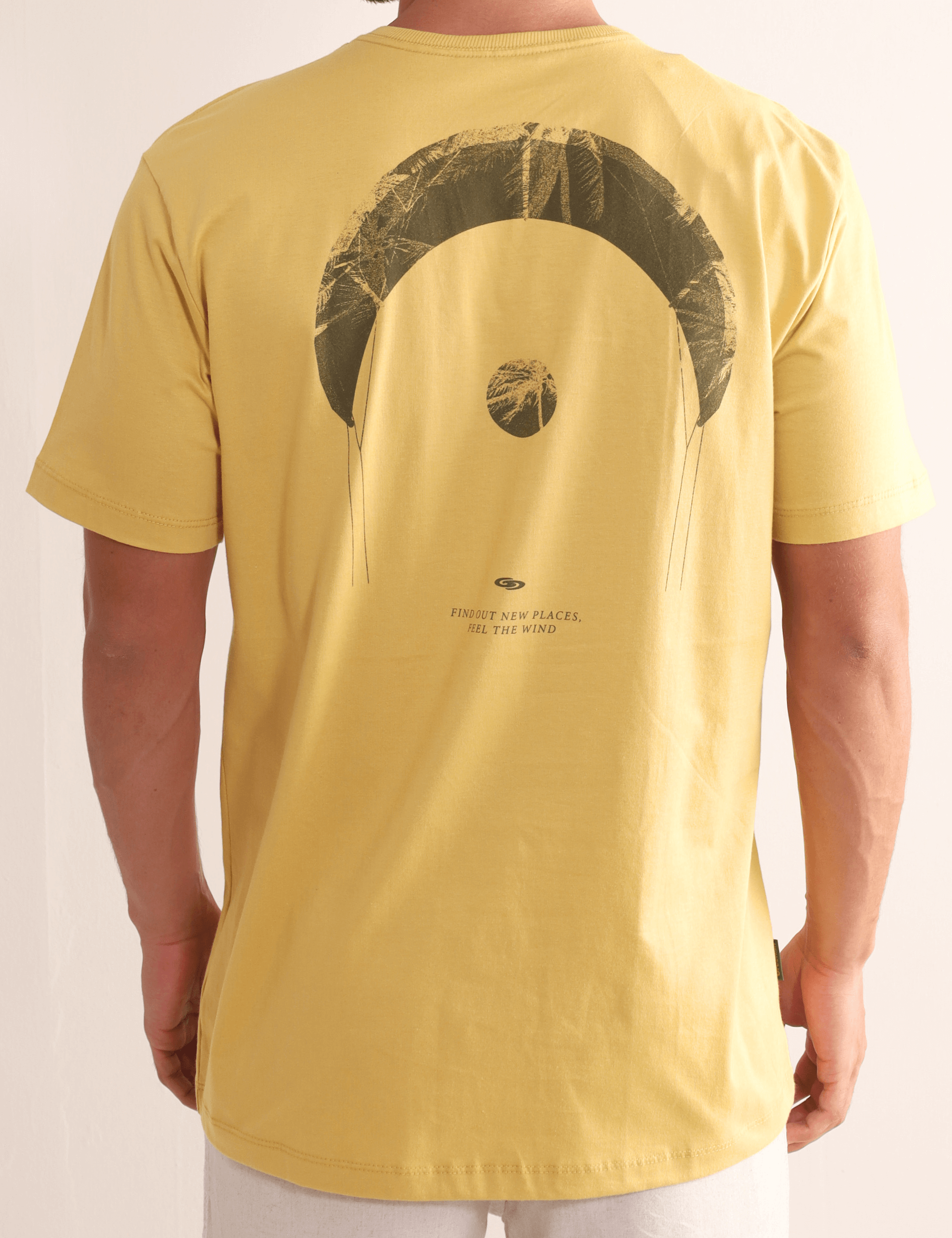 Homem vestindo Camiseta Greenish "Find Out New Places" em amarelo escuro com estampa de pipa nas costas, ideal para aventura.