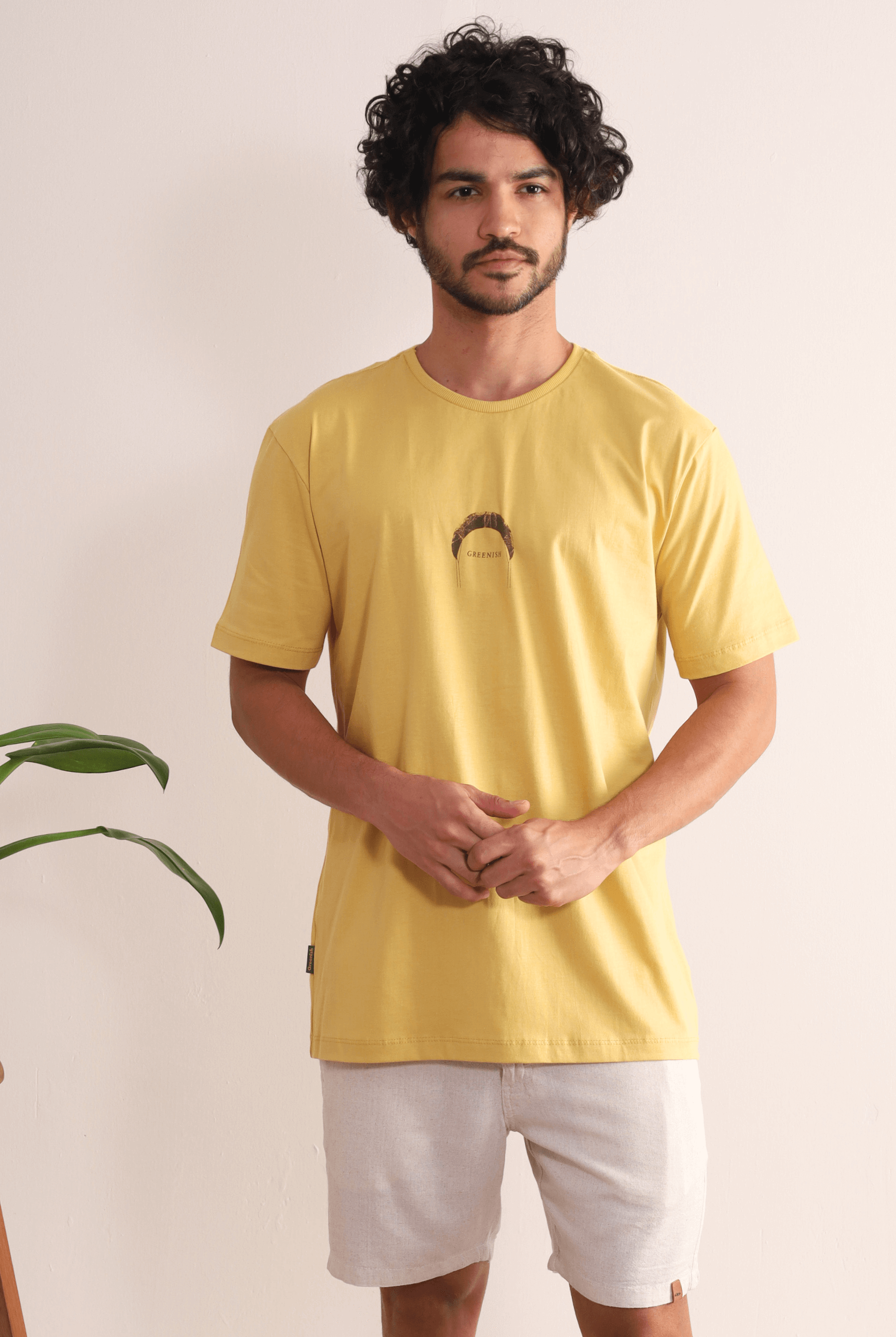 Homem vestido com a Camiseta Fund Out New Places Amarelo Escuro da Greenish, inspirada no kite, ideal para aventuras ao ar livre.