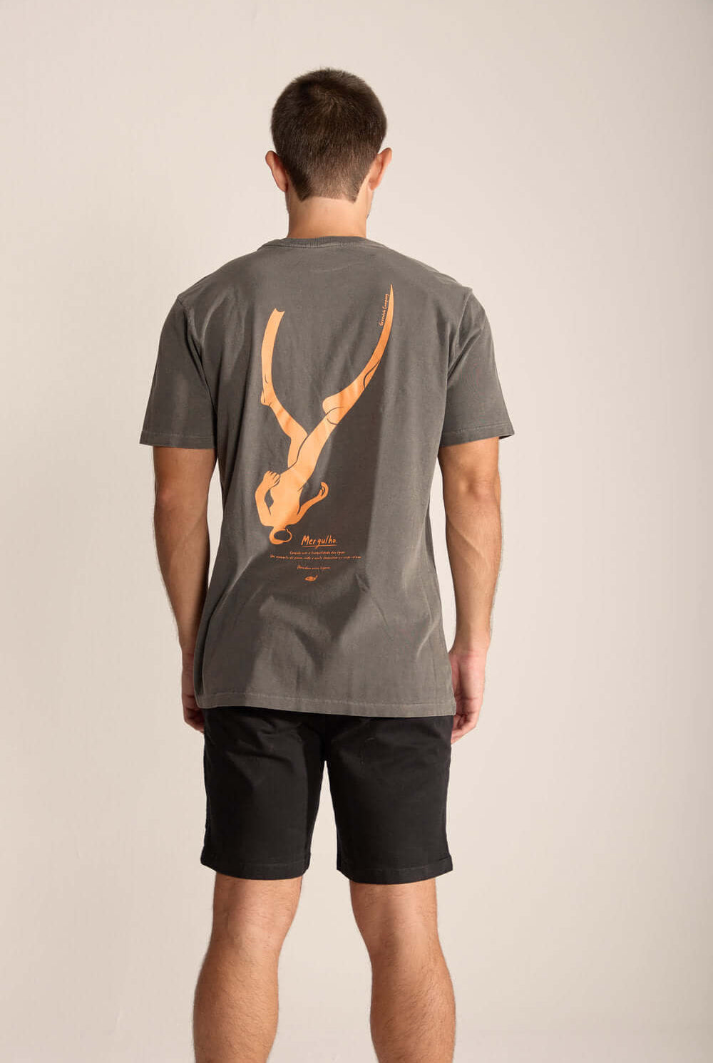 Camiseta Masculina Mergulhador da Greenish, vista de costas, estampa vibrante em fundo cinza, estilo casual.