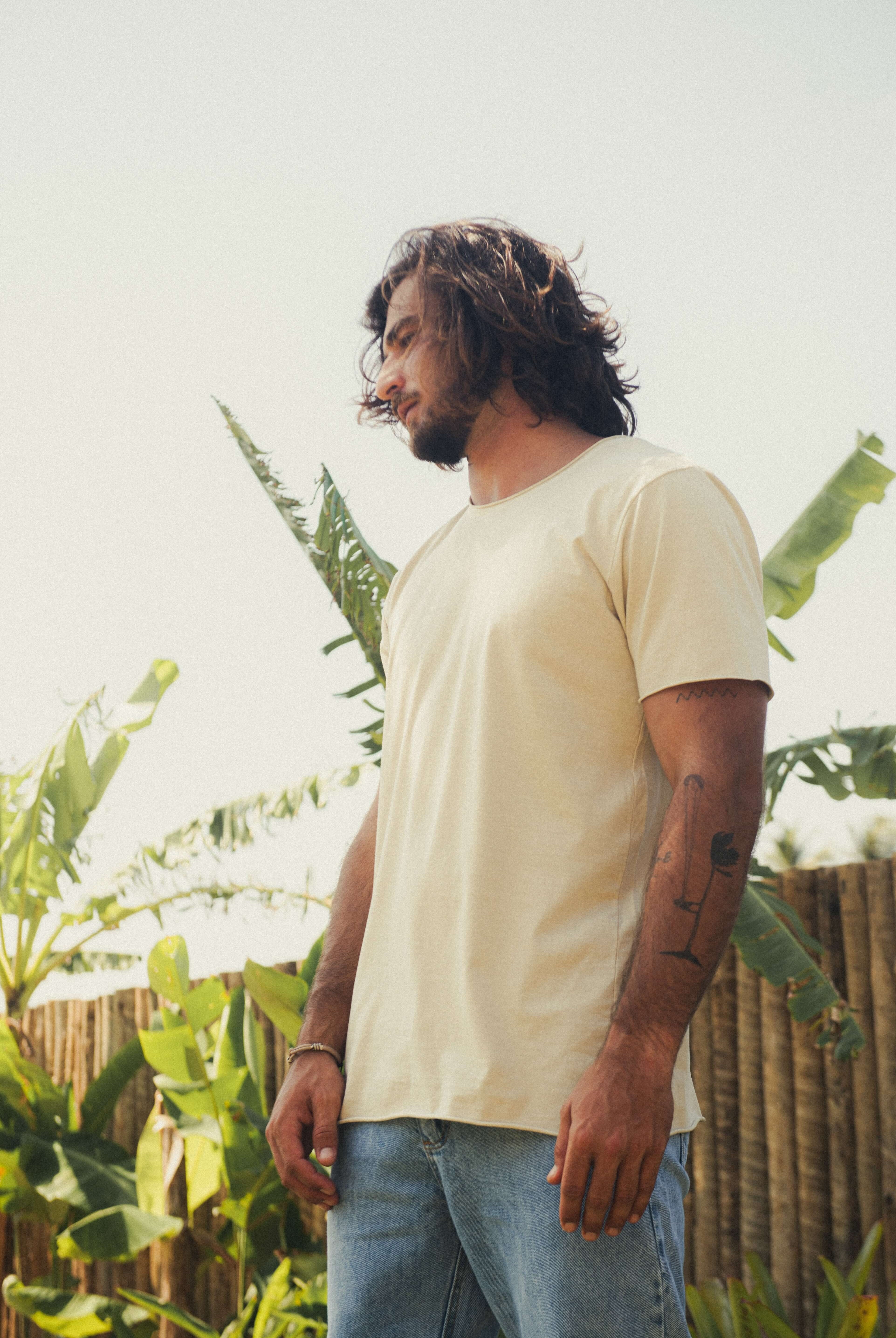Homem usando CAMISETA STONE RAWEDGE - AREIA da Greenish em cenário tropical, camiseta de algodão com visual raw e despojado.