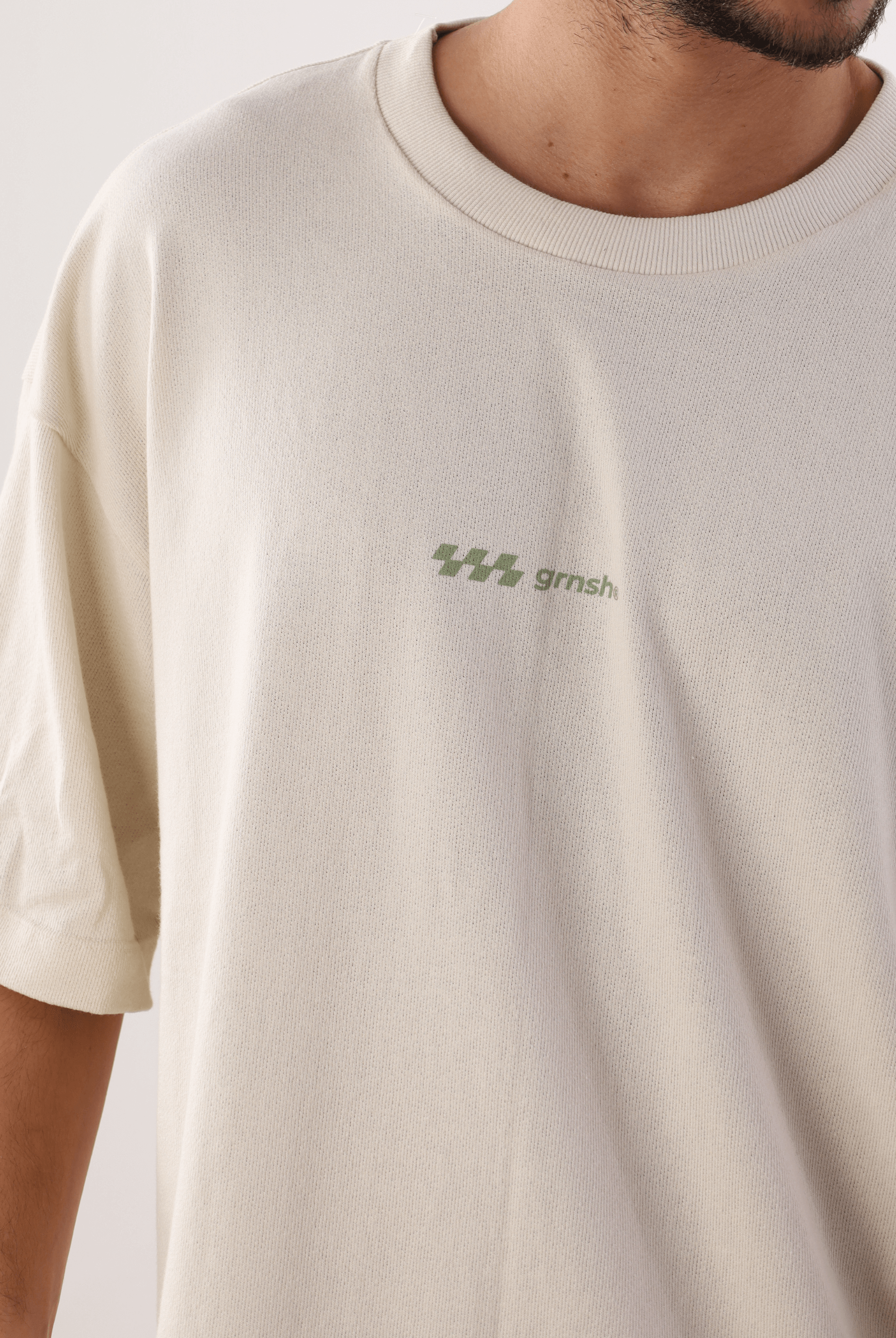 Camiseta Oversized Hexagon Lines Bege da marca Greenish, confortável e moderna, destacando logo minimalista em detalhe frontal.