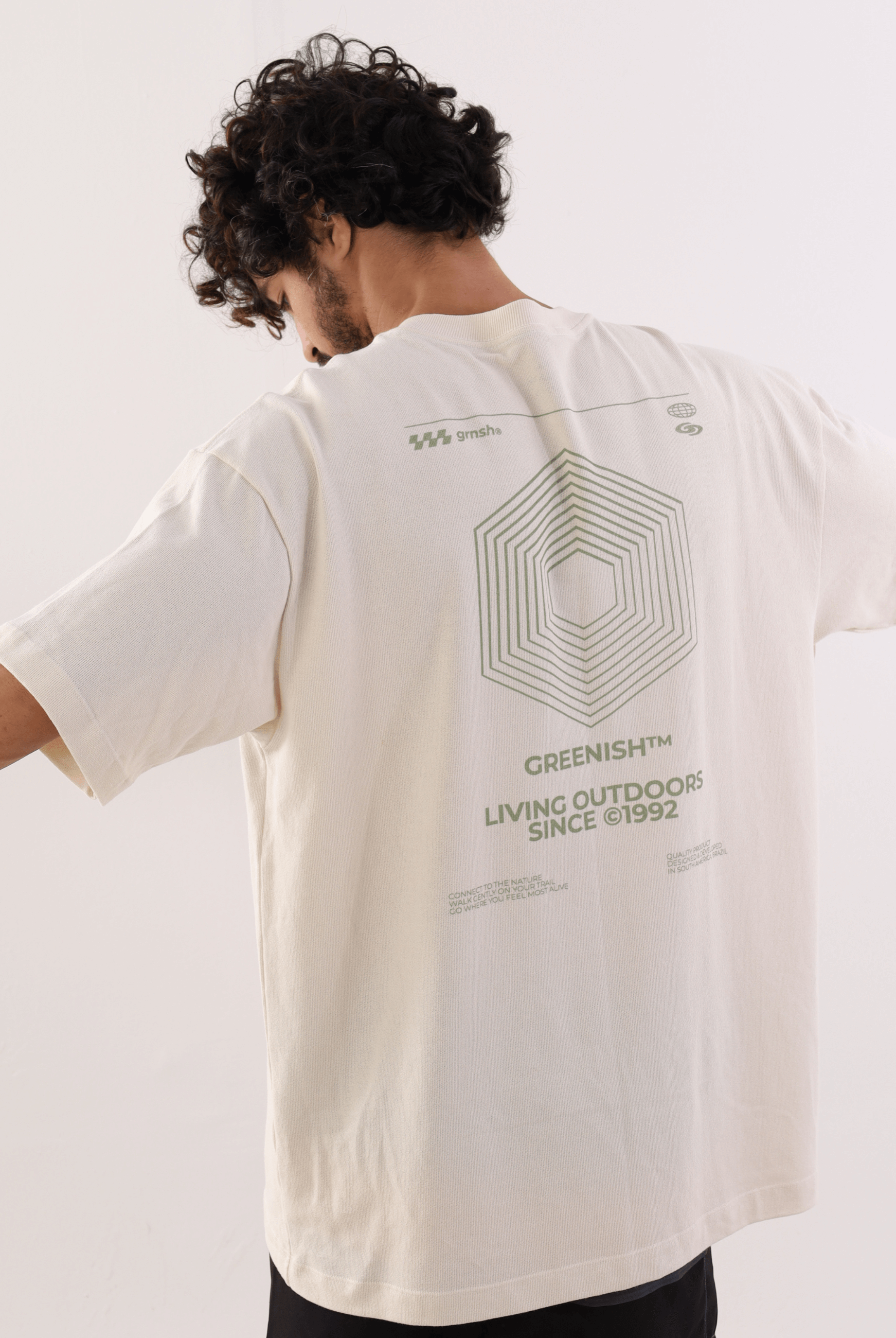 Homem vestindo Camiseta Oversized Hexagon Lines - Bege da marca Greenish, destacando design geométrico nas costas, ideal para estilo casual.