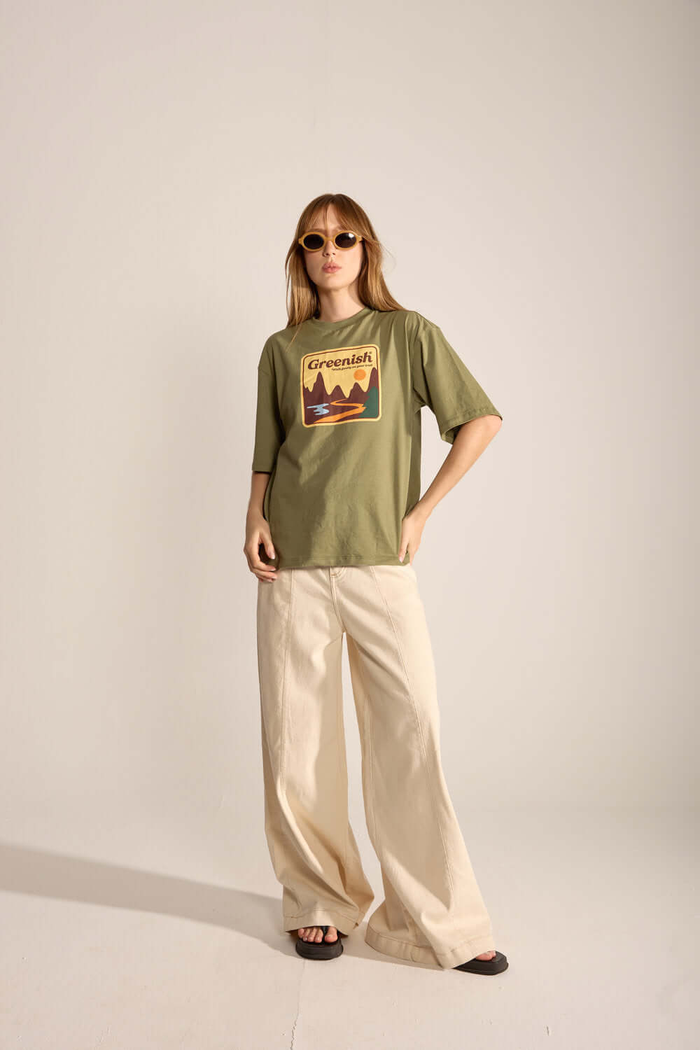Modelo usando a Camiseta Oversized Walk Gently da Greenish, em verde com estampa de montanhas e calça ampla.