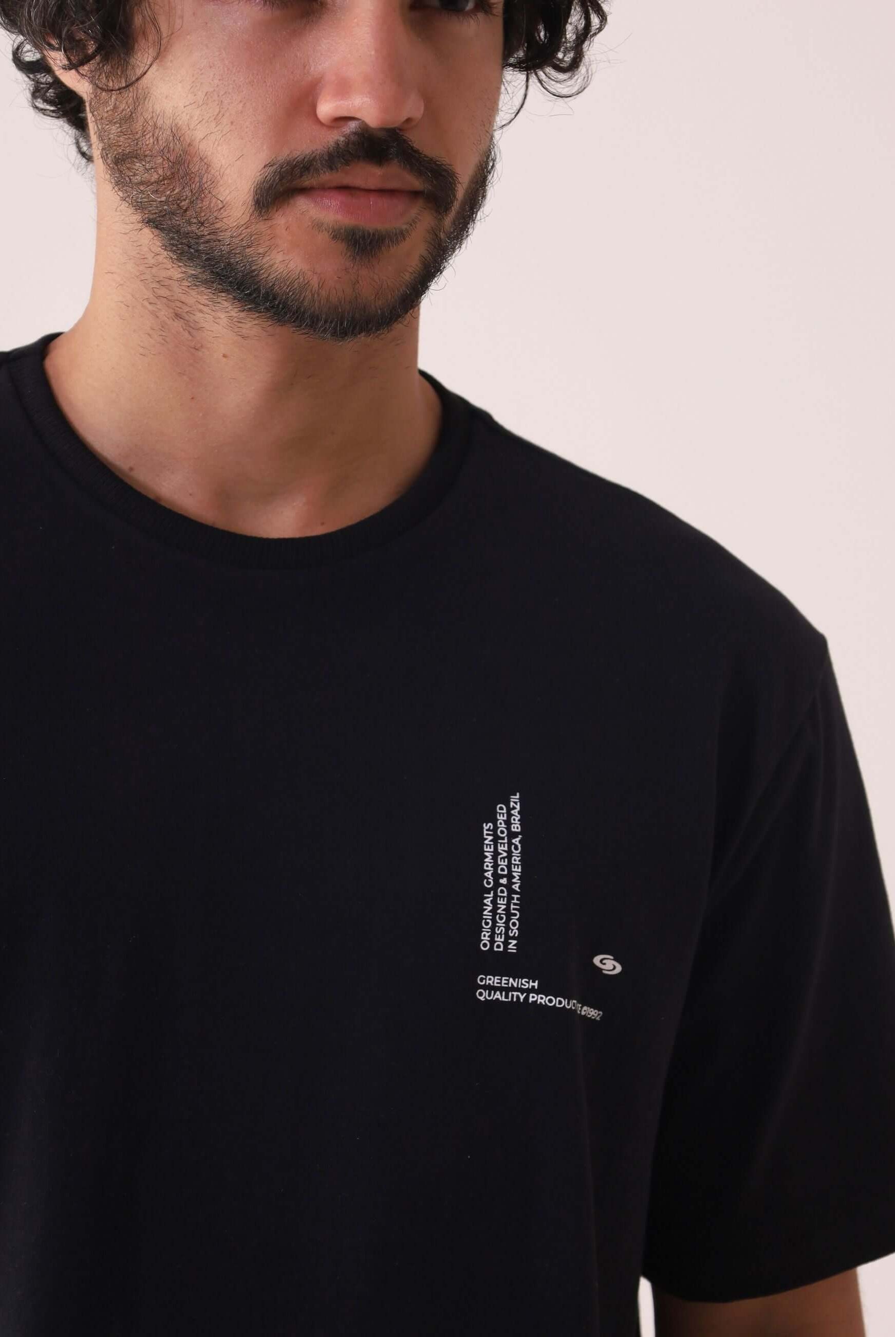 Camiserta Greenish Quality Product - Preto com silk em relevo, gola de ribana e estilo atemporal, vestindo um homem. Marca Greenish.