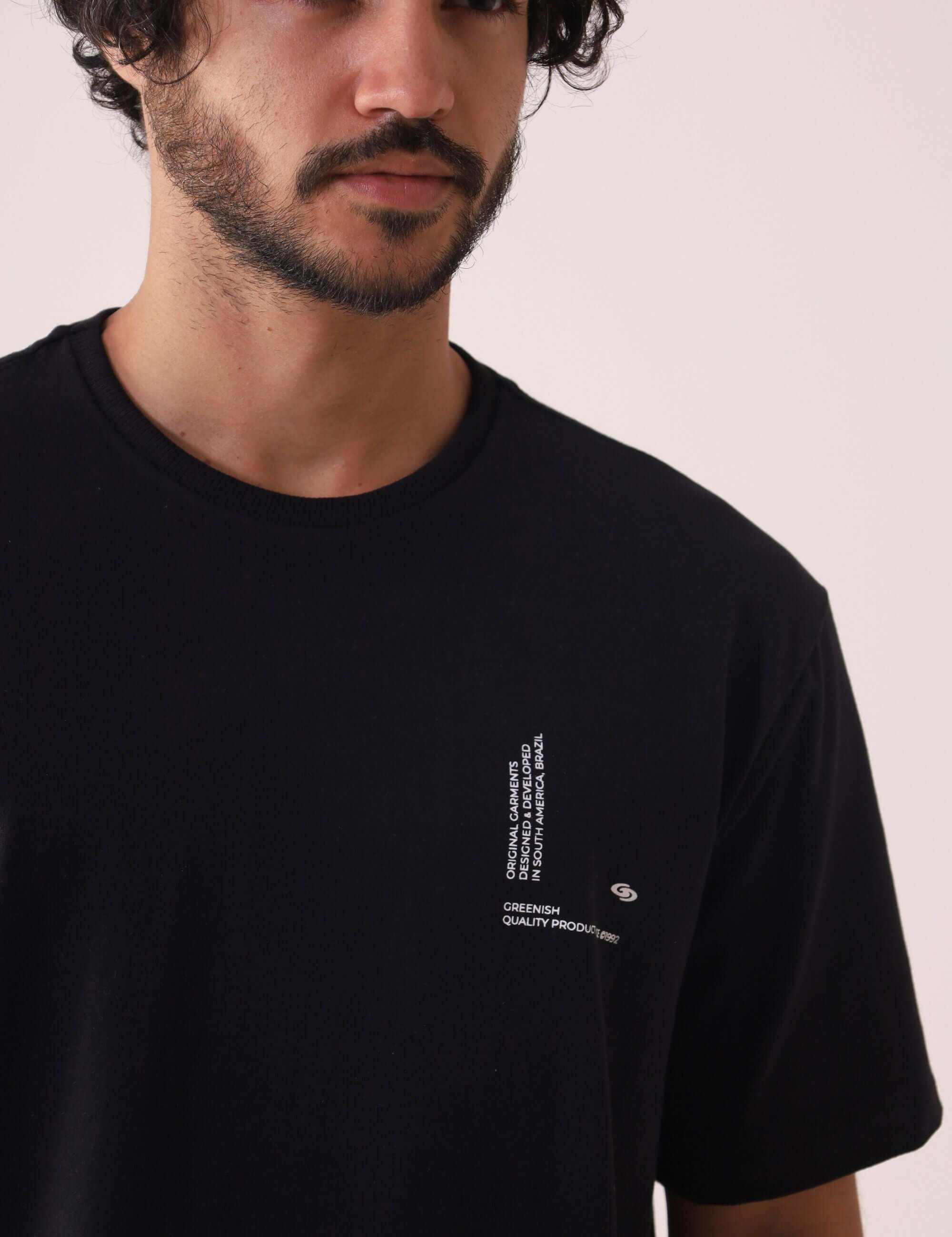 Camiserta Greenish Quality Product - Preto com silk em relevo, gola de ribana e estilo atemporal, vestindo um homem. Marca Greenish.