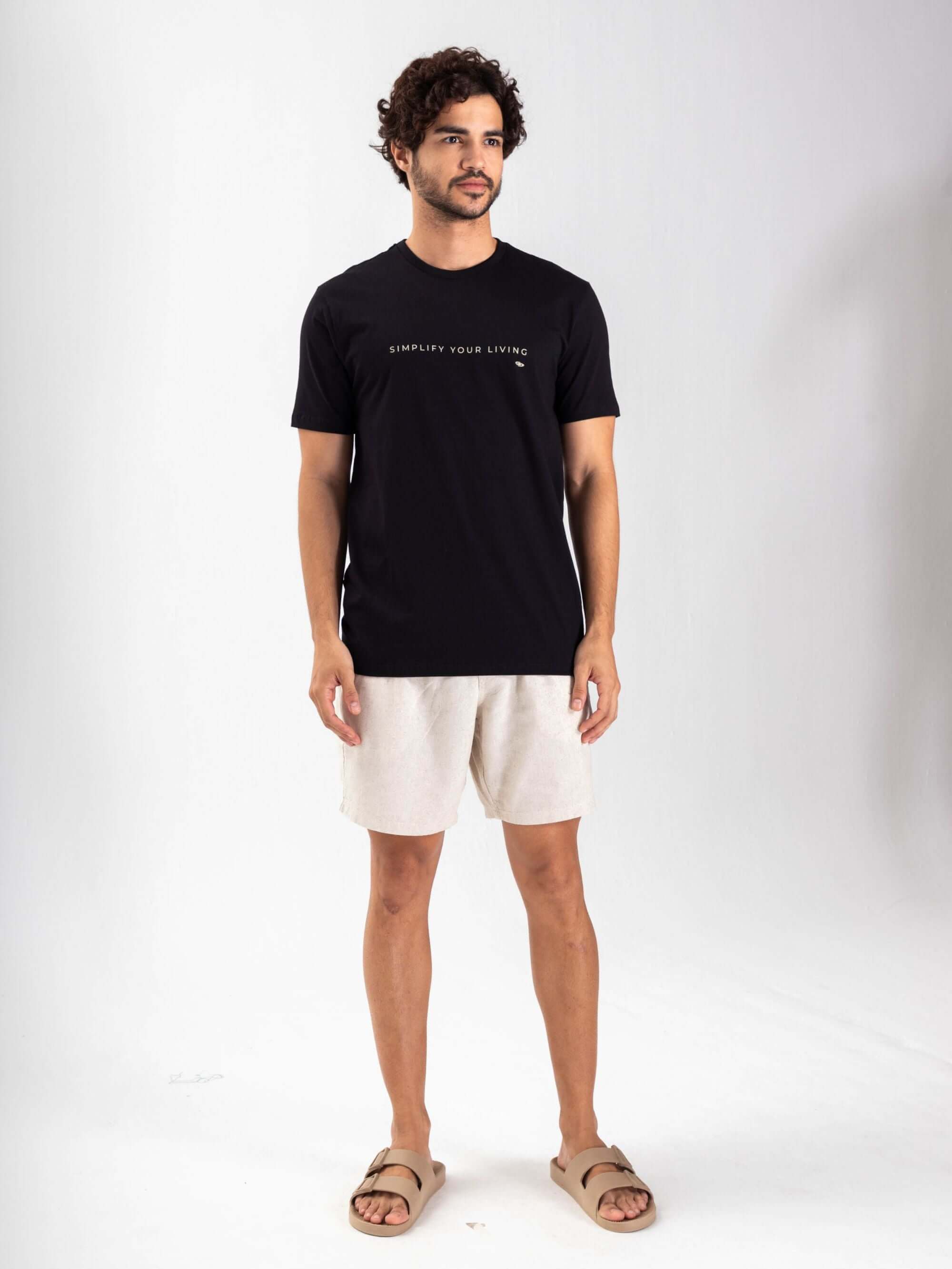 Camiseta preta 'Simplify Your Living' da Greenish, modelo masculino em pé, look descontraído.