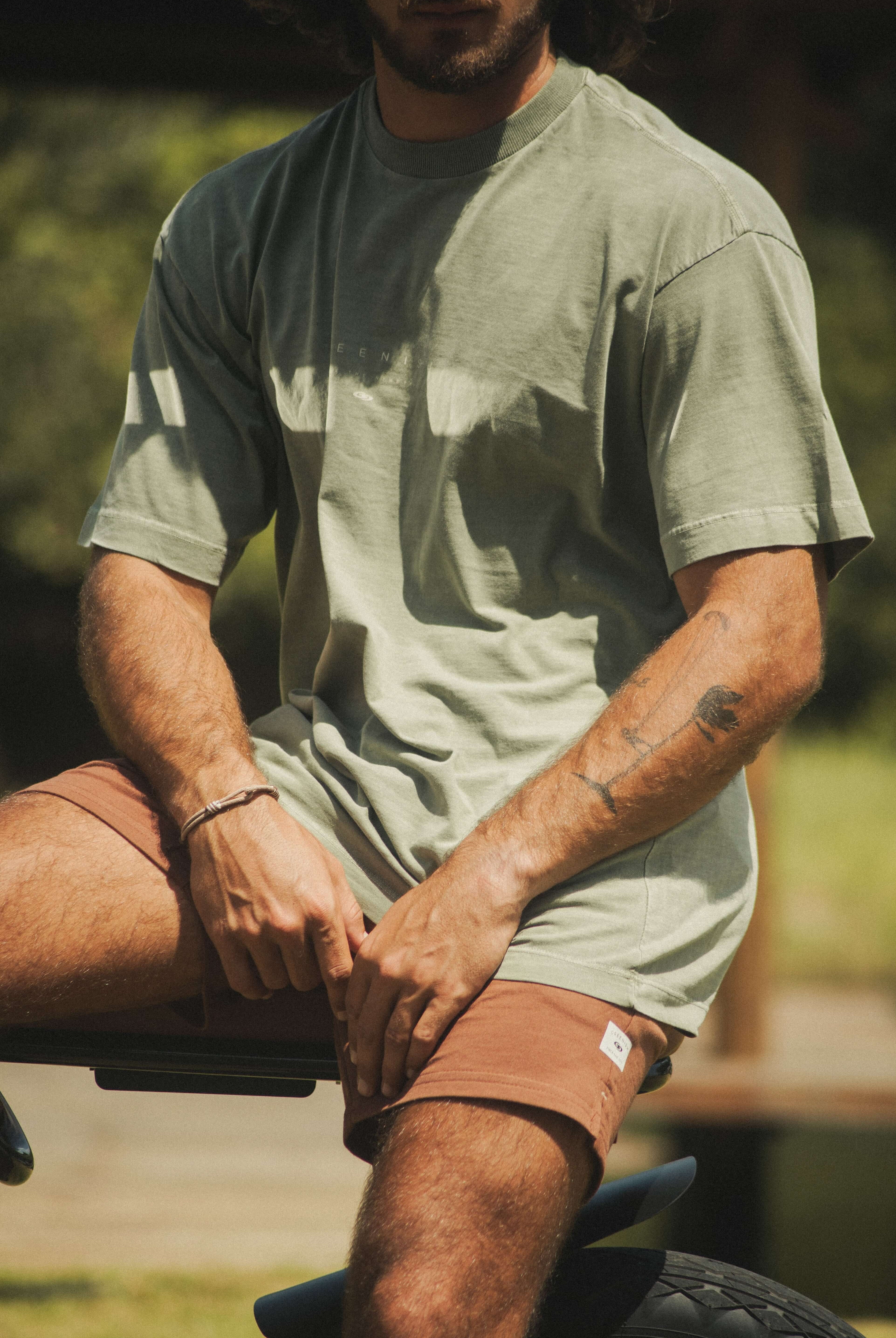 Homem vestindo Camiseta Stone Oversized Greenish - Verde da marca Greenish, em ambiente ao ar livre, com design moderno e estilo vintage.