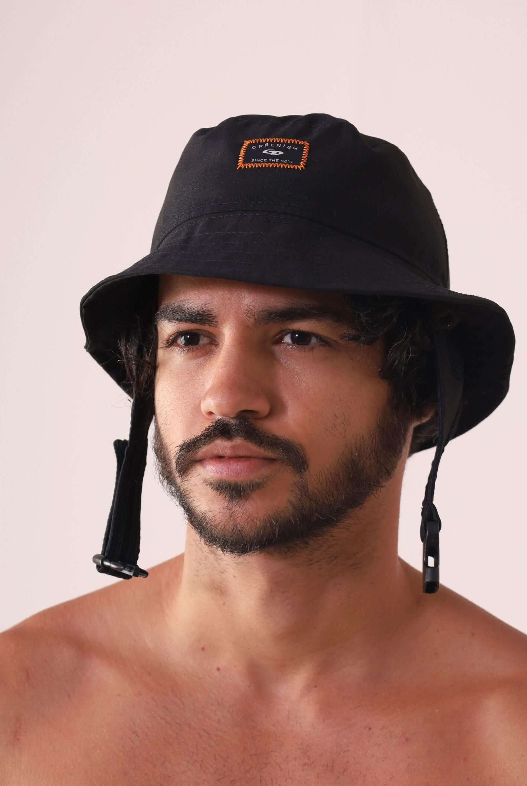 Homem usando CHAPEU BUCKET SPORT - PRETO da marca Greenish, com aba maleável e queixo ajustável, ideal para aventuras ao ar livre.