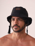 Homem usando CHAPEU BUCKET SPORT - PRETO da marca Greenish, com aba maleável e queixo ajustável, ideal para aventuras ao ar livre.