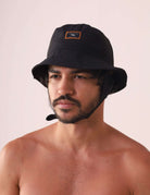 Homem usando CHAPEU BUCKET SPORT - PRETO com etiqueta Greenish e design técnico para atividades ao ar livre.