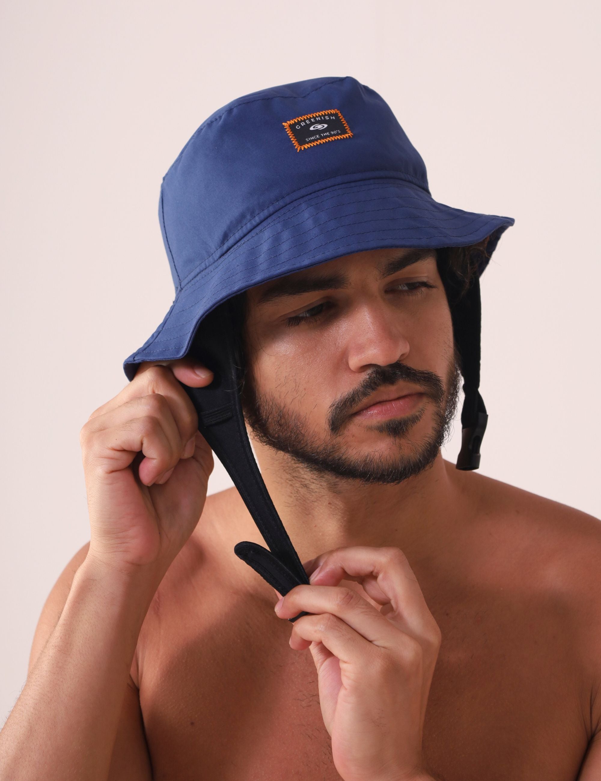 Homem ajustando Chapeu Bucket Sport - Azul Marinho da Greenish para atividades ao ar livre.
