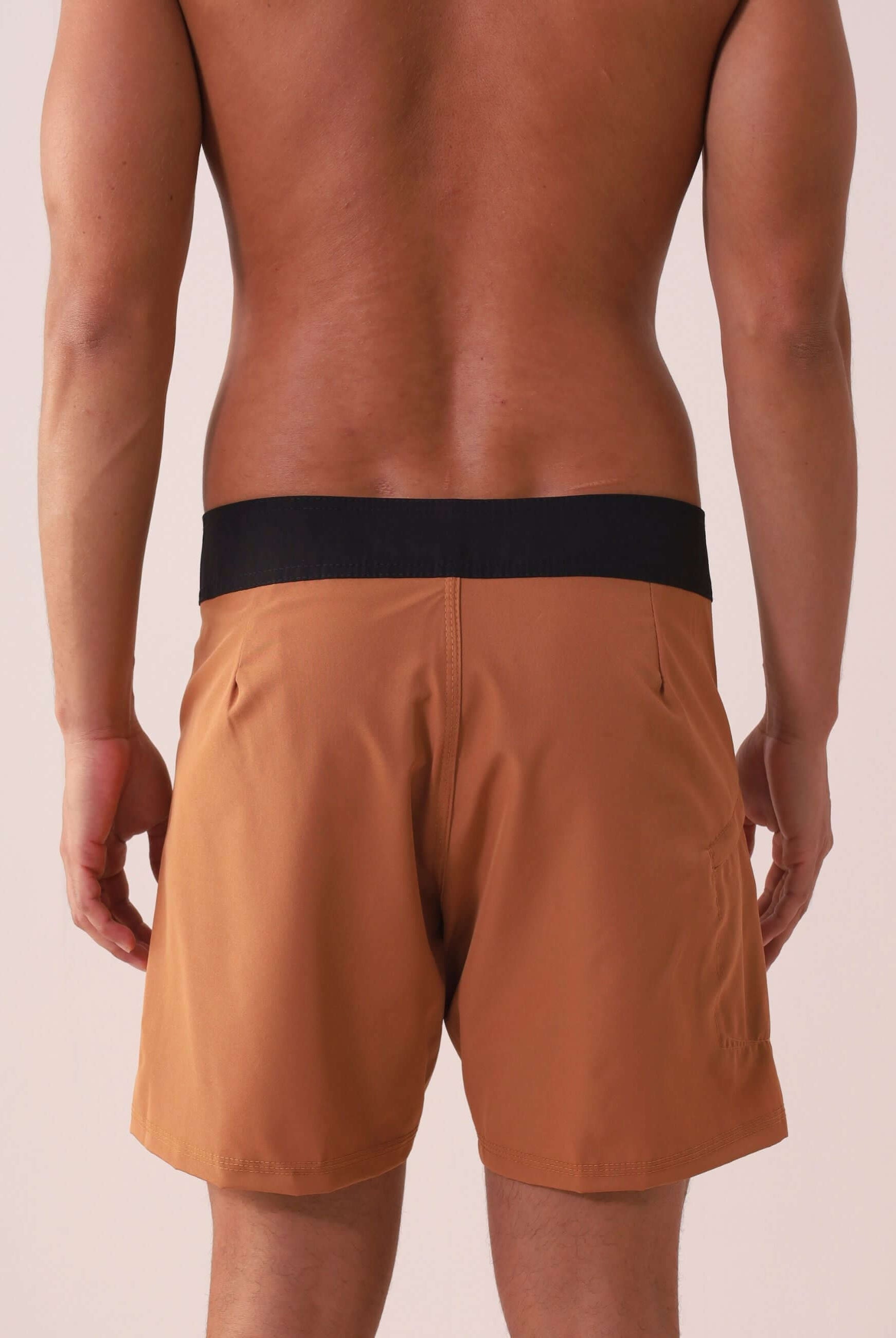 Homem vestindo BOARDSHORT CLASSIC TRUNK ESSENCIAL - CAQUI da Greenish, destacando modelagem anatômica e bolso funcional.