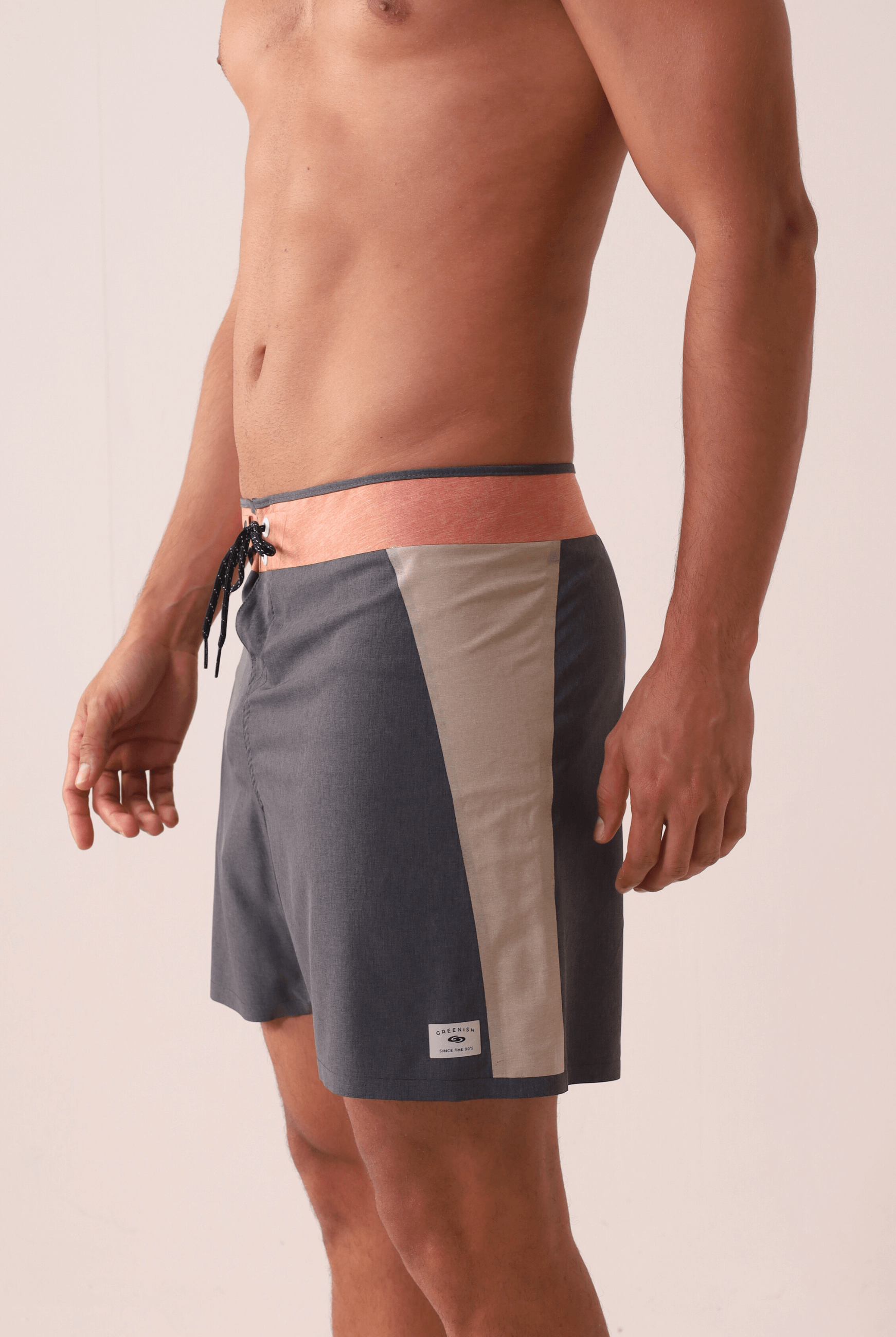 Homem vestindo Boardshort Ultralight II Sunset - Preto da marca Greenish, com design multicolorido e recortes colados sem costura.