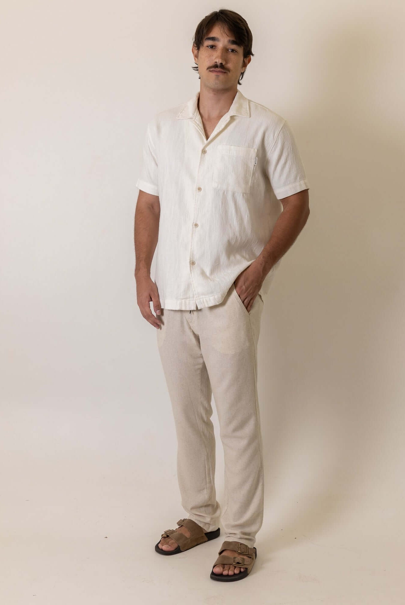 Homem vestindo Camisa Botao High Tide - Off White da marca Greenish, destacando um estilo casual e elegante em tom claro.
