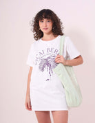 Mulher vestindo Camiseta Açai Berry da Greenish, off white, 100% algodão, estilo despojado e confortável com estampa tropical.