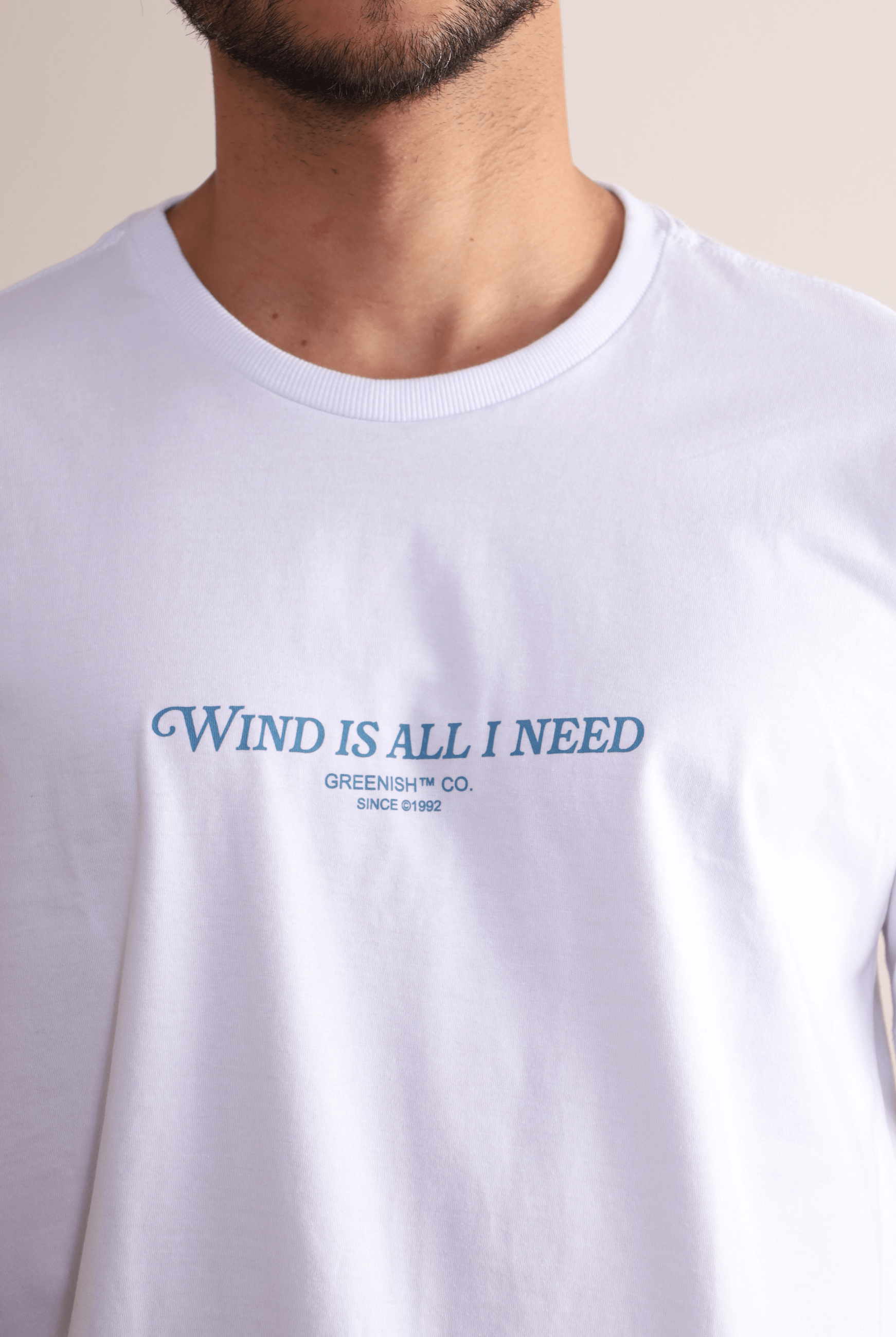 Camiseta branca Greenish 'Wind is All I Need' com estampa frontal, leve, estilosa e confortável, perfeita para movimento.