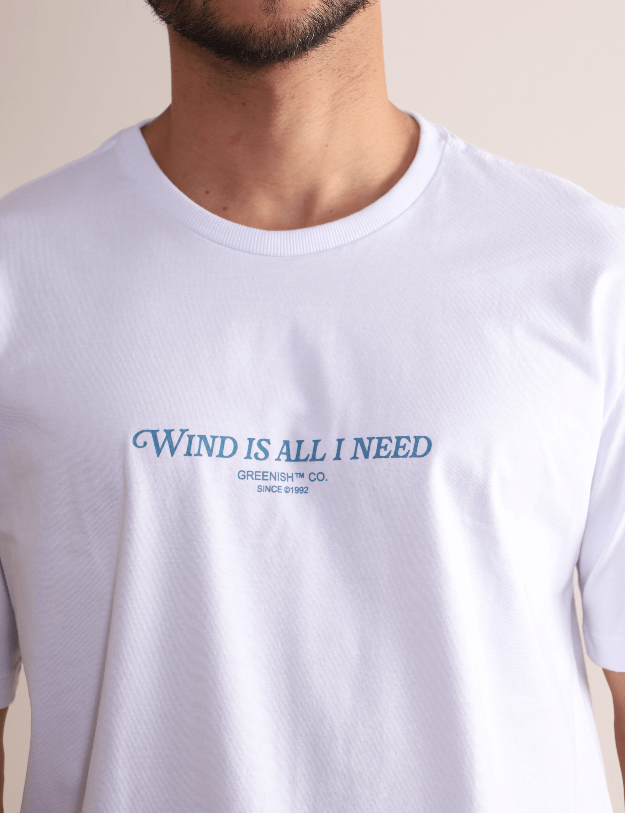 Camiseta branca Greenish 'Wind is All I Need' com estampa frontal, leve, estilosa e confortável, perfeita para movimento.