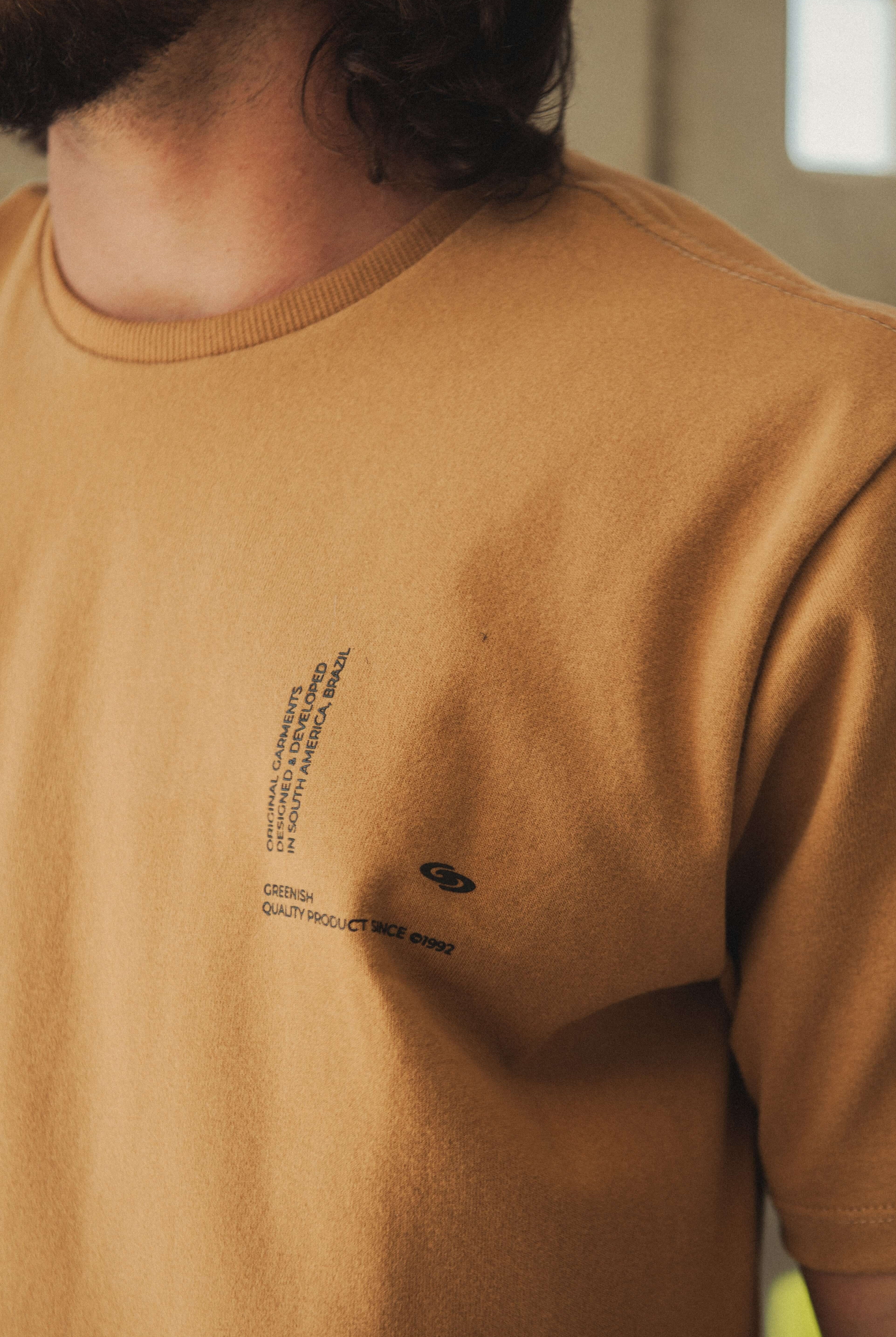 Camiseta Greenish Quality Product - Caqui com design minimalista e silk localizado, ideal para uso diário com conforto e estilo.