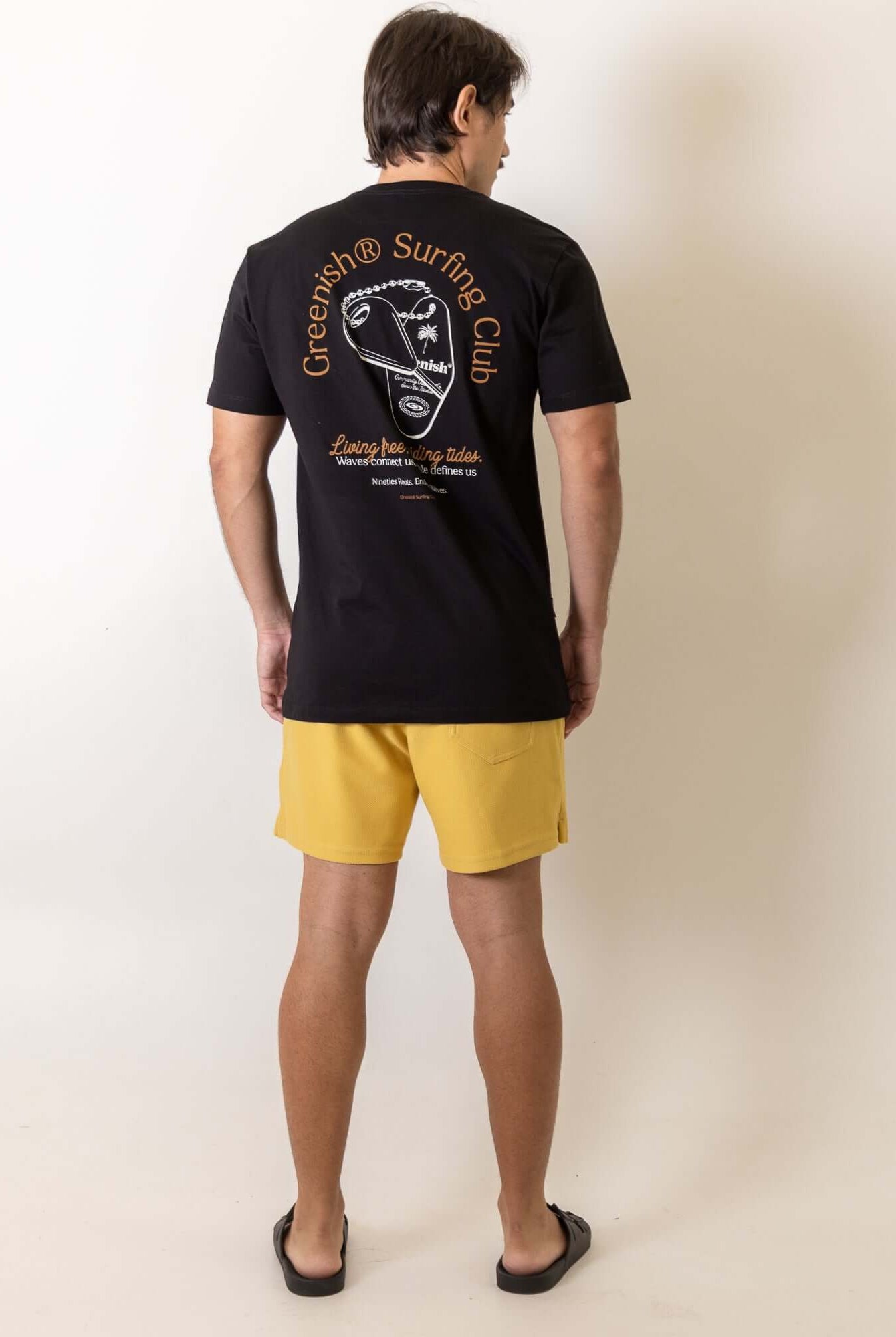 Homem vestindo Camiseta Fin Key - Preto da Greenish com design vintage e espírito surfista, destacando bordado retrô nas costas.