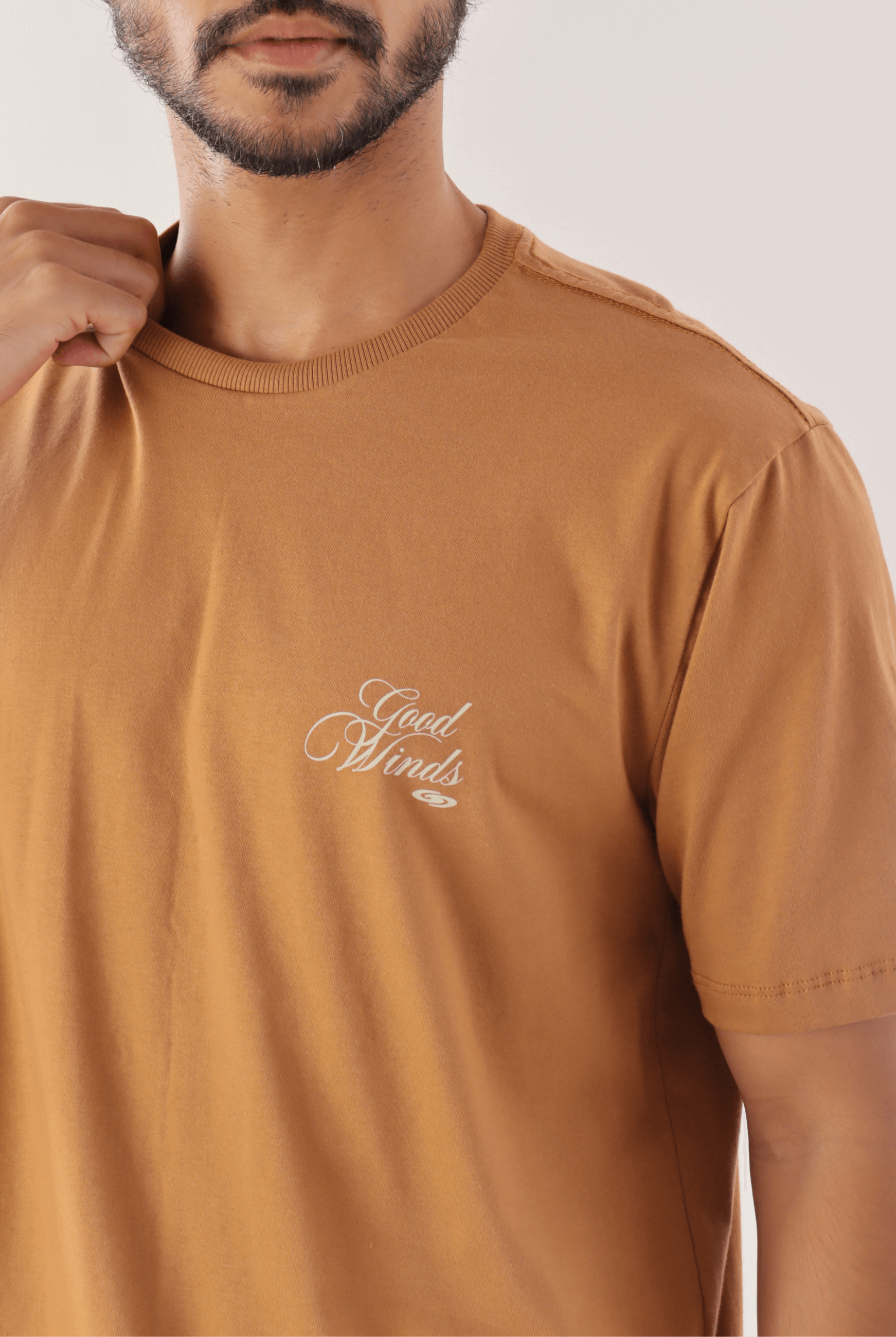 Homem vestindo camiseta marron 'Kites & Good Winds' da Greenish, destacando o design elegante e confortável para amantes de esportes ao ar livre.