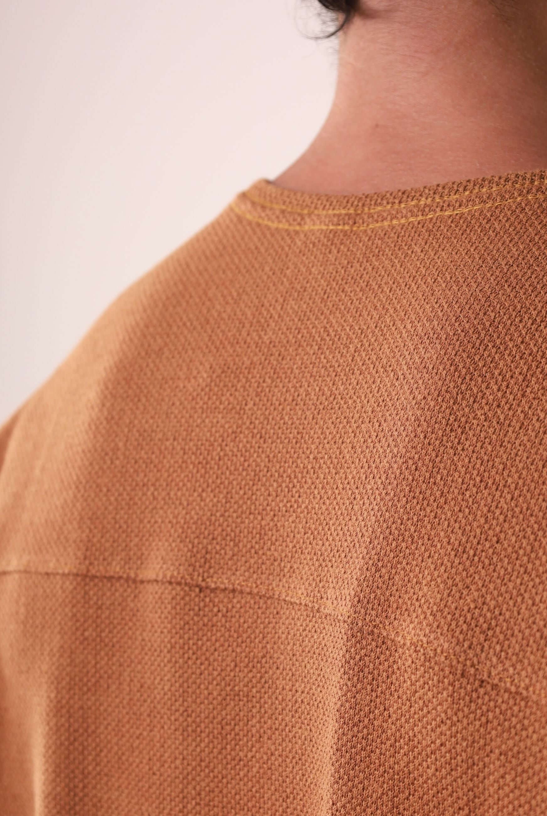 Detalhe das costas da CAMISETA MARÉ - CAQUI da Greenish, destacando a pala reforçada e tecido sofisticado em algodão, poliéster e elastano.