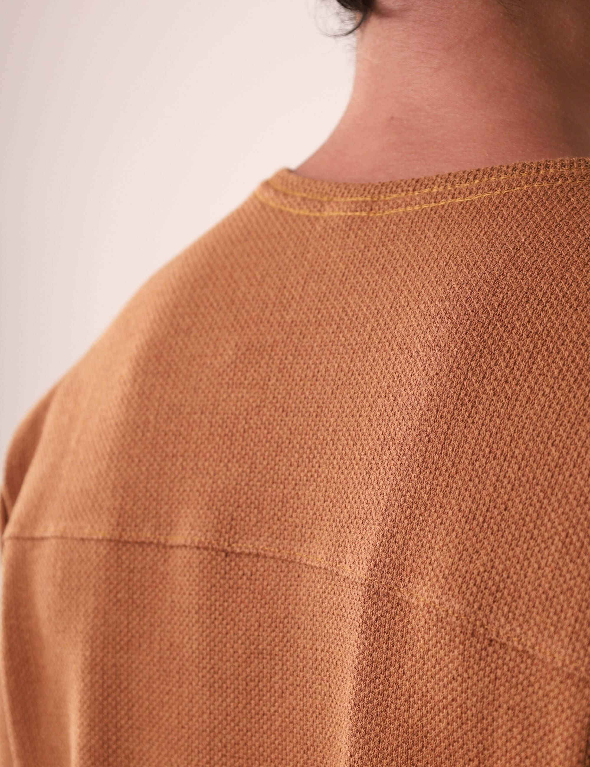 Detalhe das costas da CAMISETA MARÉ - CAQUI da Greenish, destacando a pala reforçada e tecido sofisticado em algodão, poliéster e elastano.