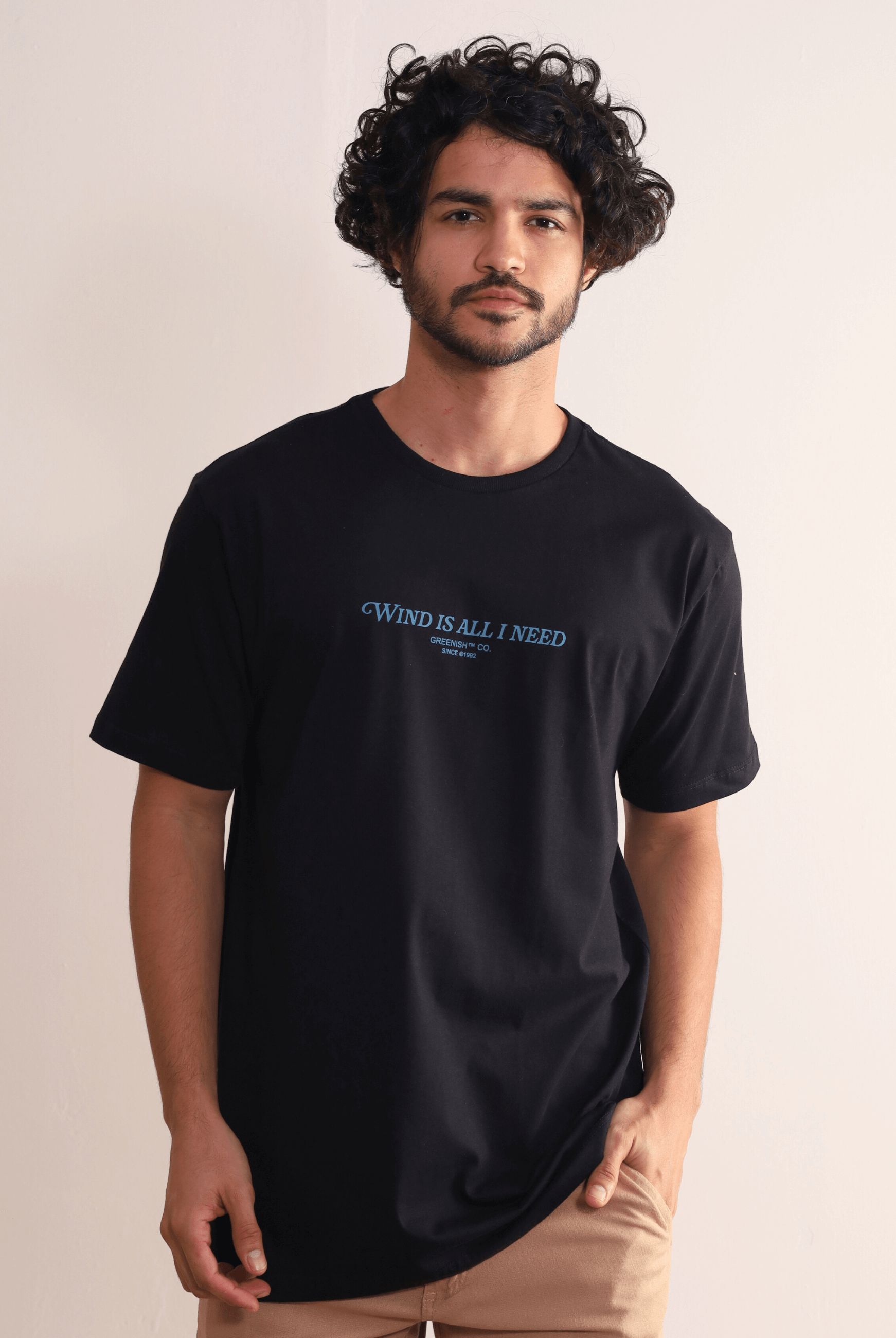 Camiseta preta Greenish 'Wind Is All I Need' com modelagem confortável e estampa frontal, perfeita para estilo e conforto.