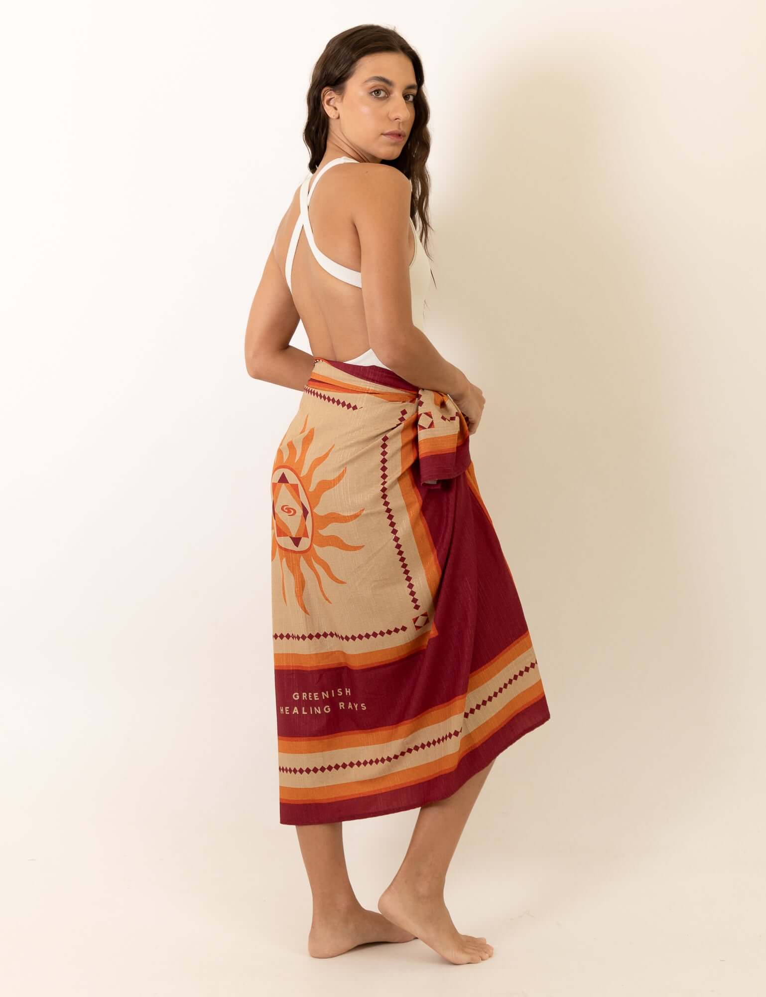 Mulher usando Canga Healing Rays - Bordo da Greenish, estampa exclusiva com referências solares e estética vintage à beira-mar.