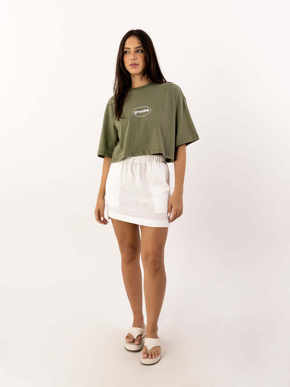 Modelo usando cropped oversized verde da Greenish com saia branca, look moderno e confortável.